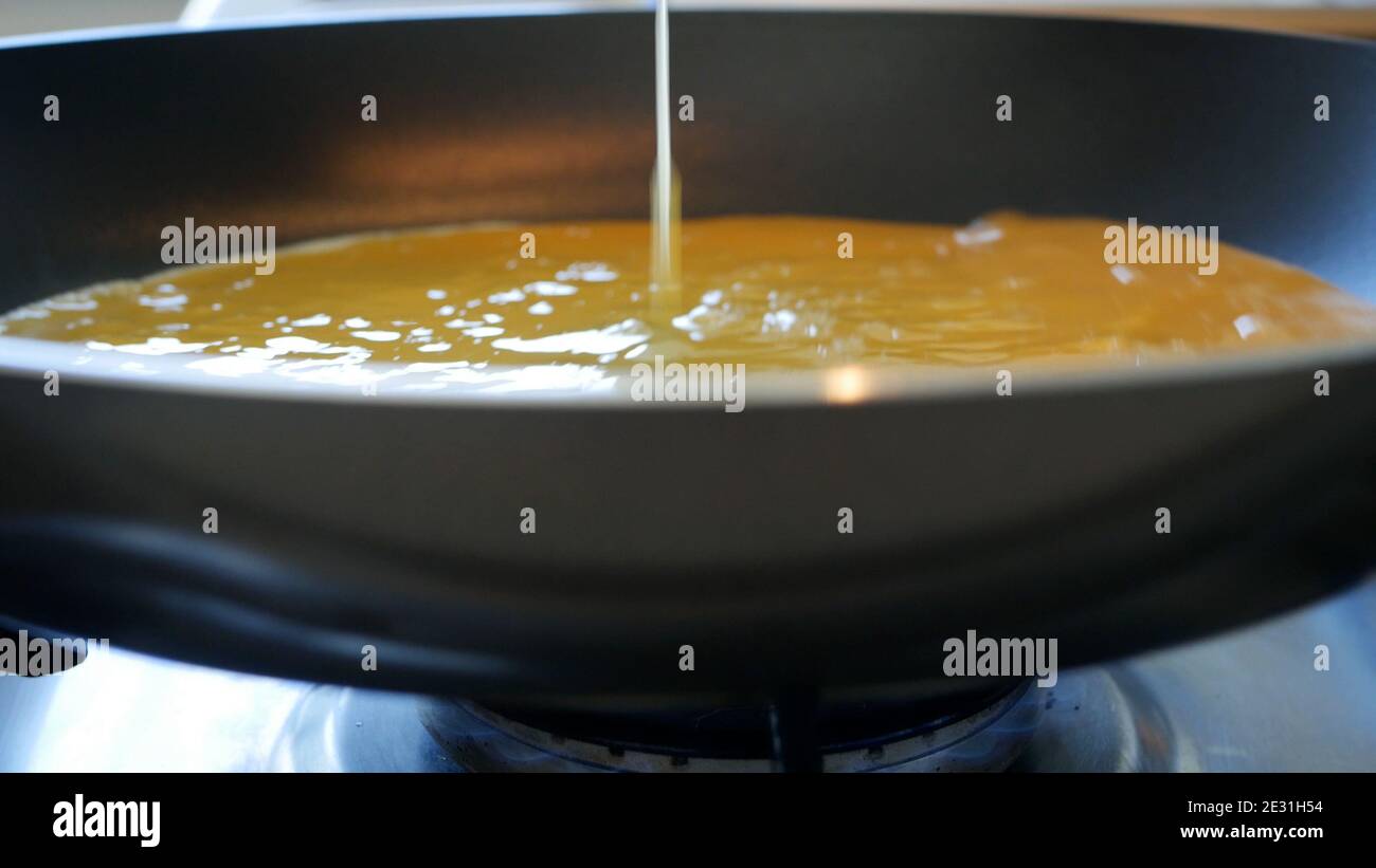 Ein Omelett in einer heißen Pfanne beim Kochen zubereiten Herd Stockfoto