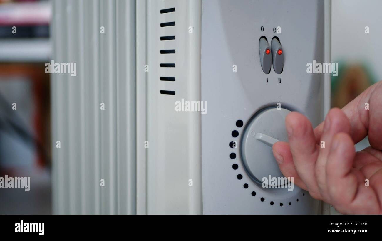 Bild mit der Hand: Einstellen des Thermostaten für den Elektroheizer zum Erwärmen eines kalten Raums Stockfoto