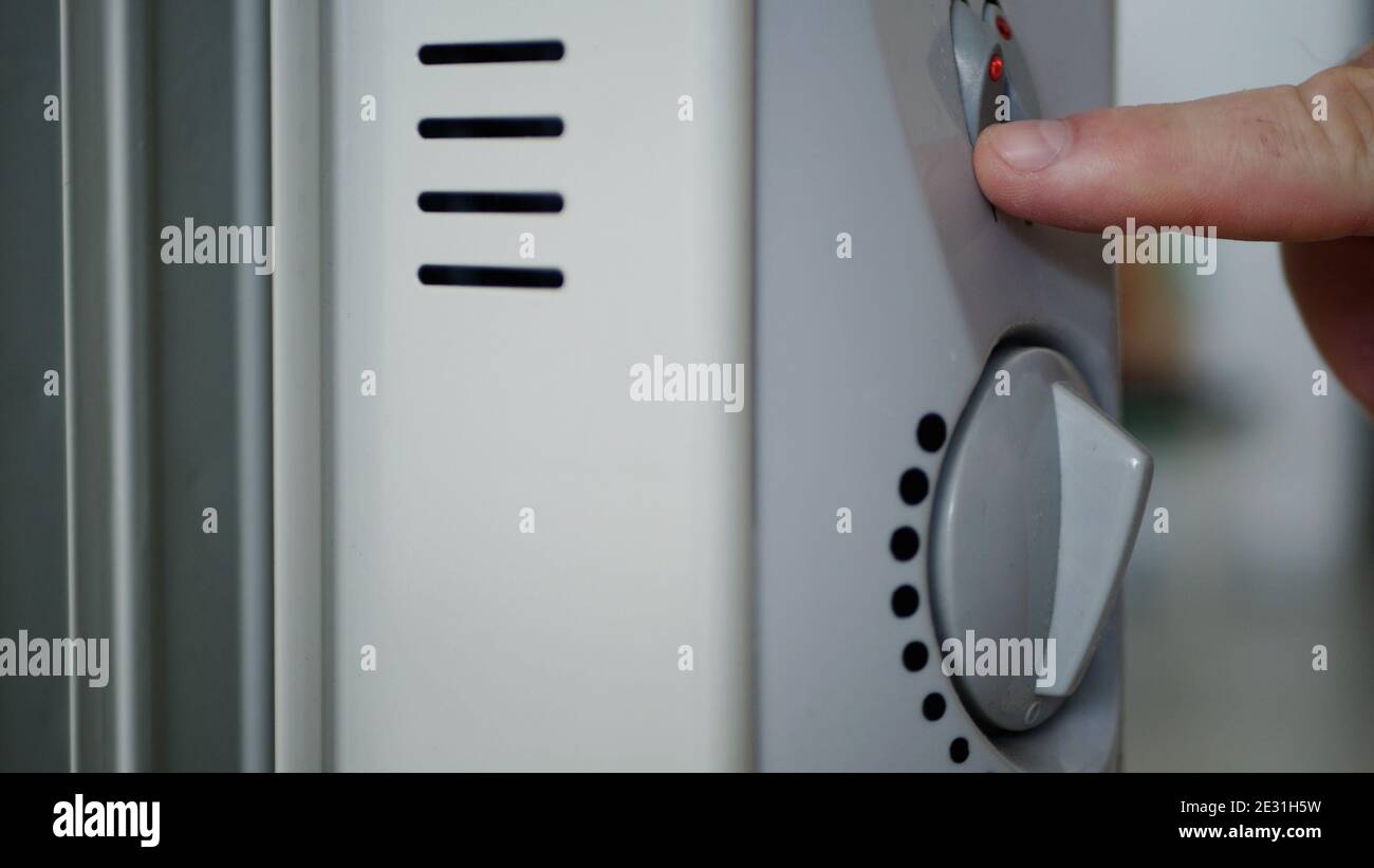 Bild mit der Hand: Einstellen des Thermostaten für den Elektroheizer zum Erwärmen eines kalten Raums Stockfoto