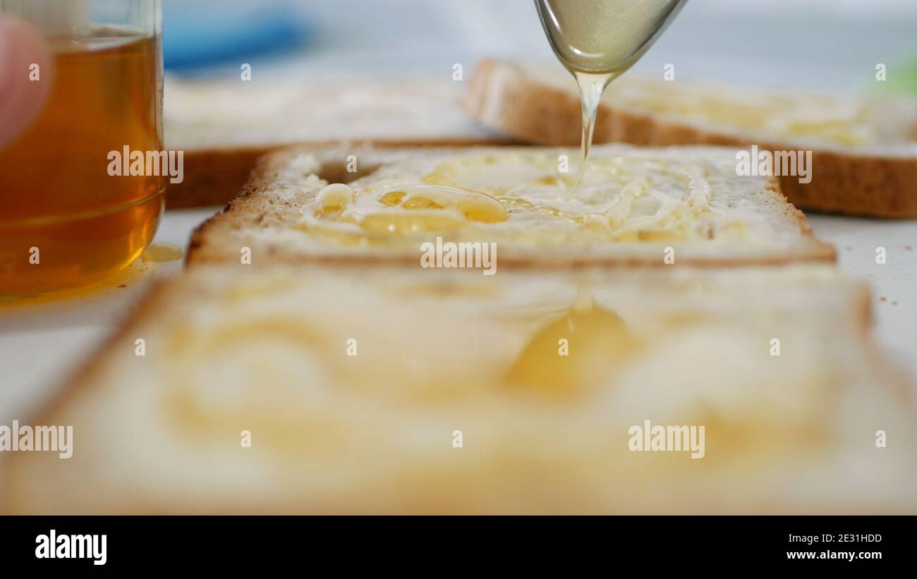 Frühstück am Morgen mit einer Person Verteilung Sweet Honey auf ein Toast Stockfoto