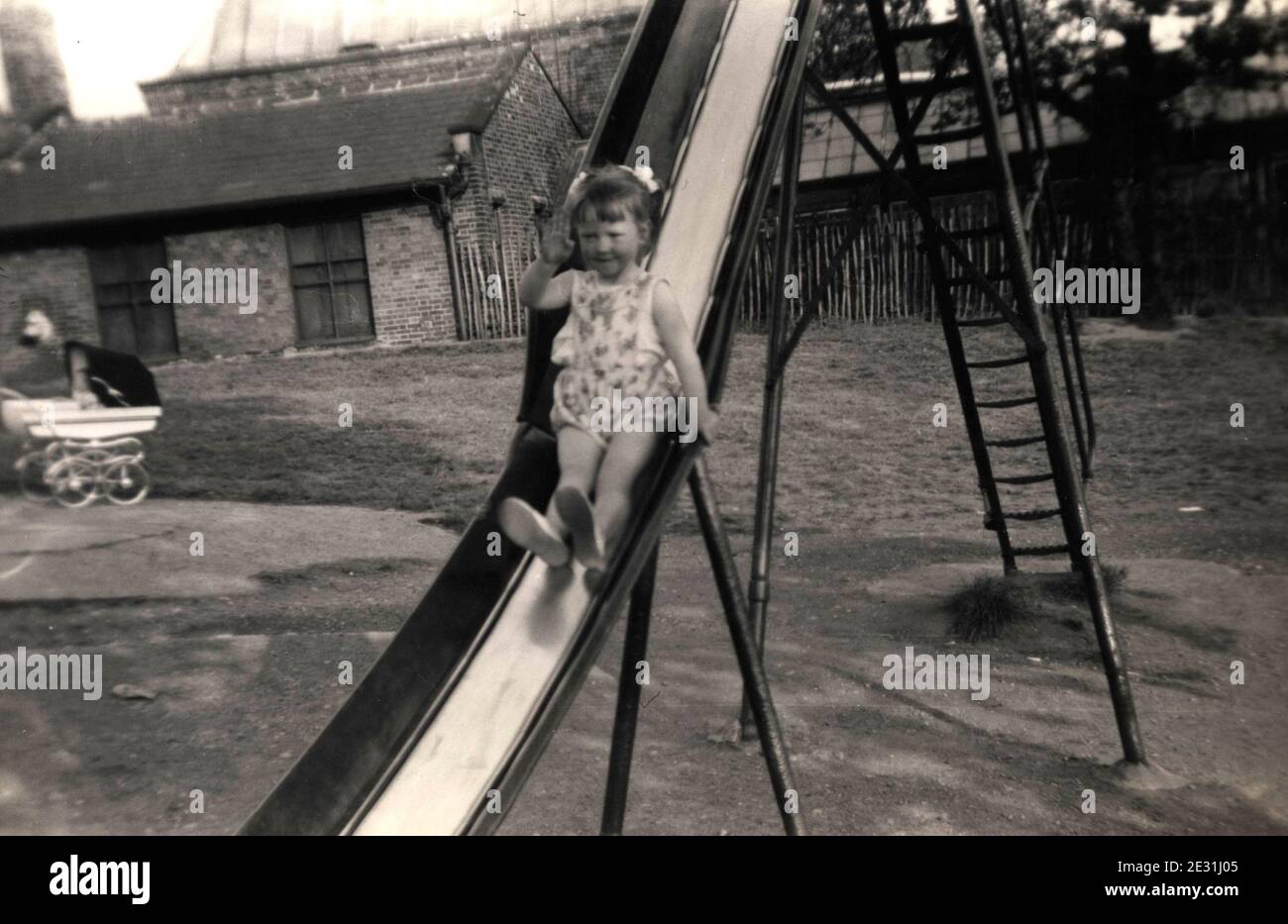 Vierjähriges Mädchen auf einer Rutsche in einem Werneth Park Spielplatz in Oldham, Lancashire in den 1960er Jahren Stockfoto