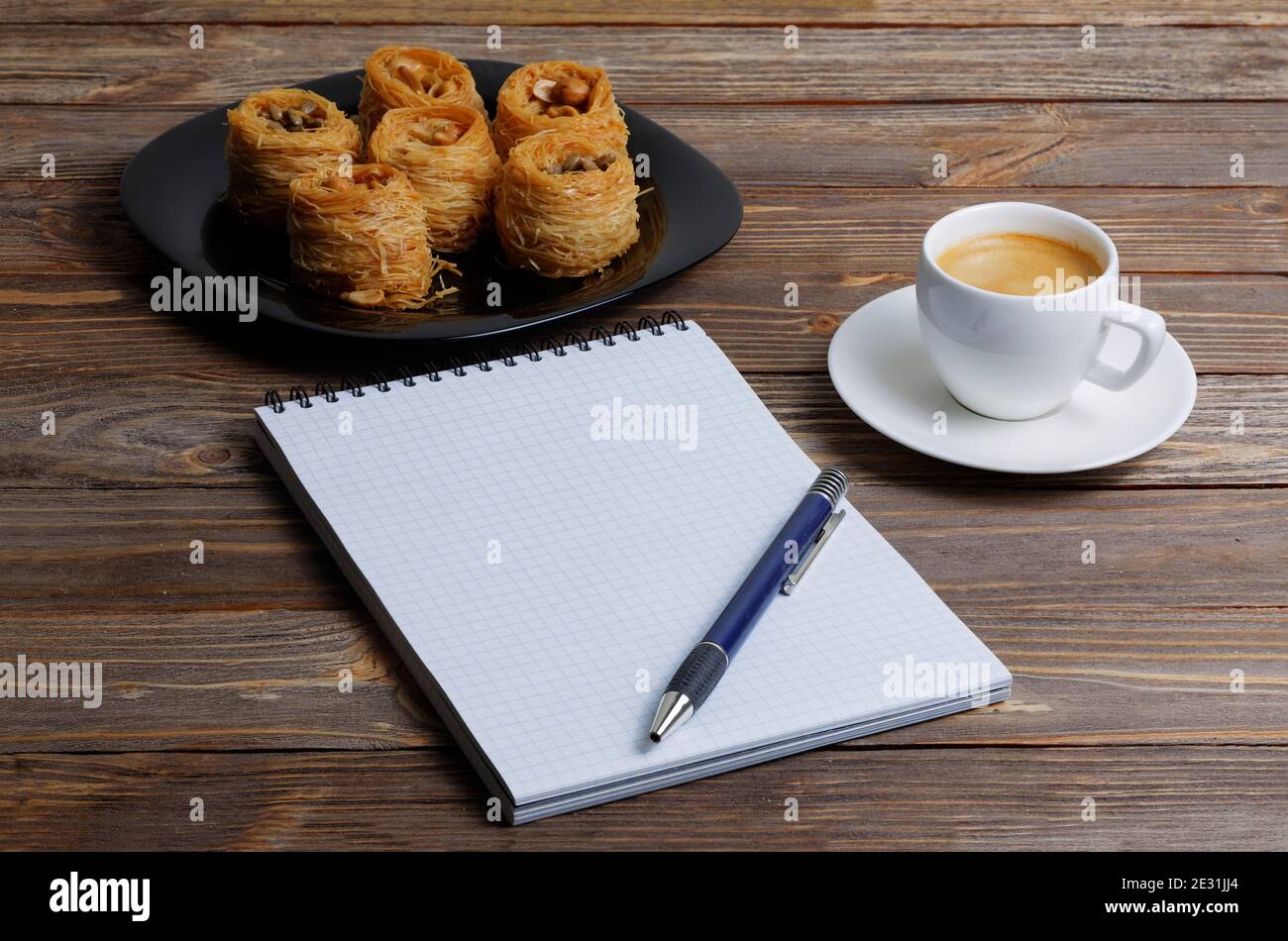 Öffnen Sie Notizbuch, Stift, Tasse Kaffee Espresso und östlichen Süßigkeiten auf Holztisch Stockfoto