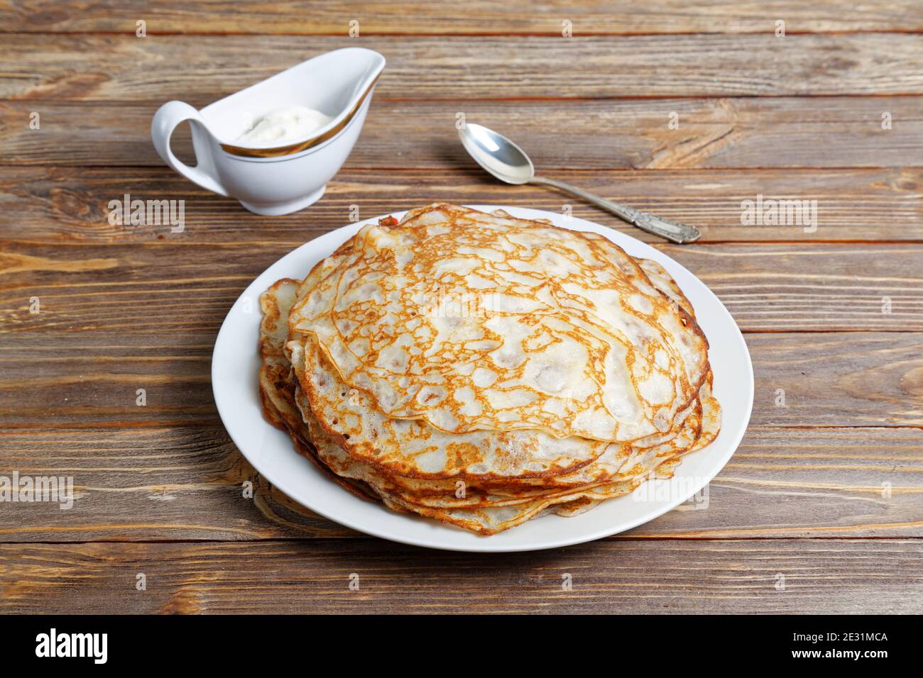 Pfannkuchen auf dem Teller und Sauerrahm auf dem Holztisch Stockfoto