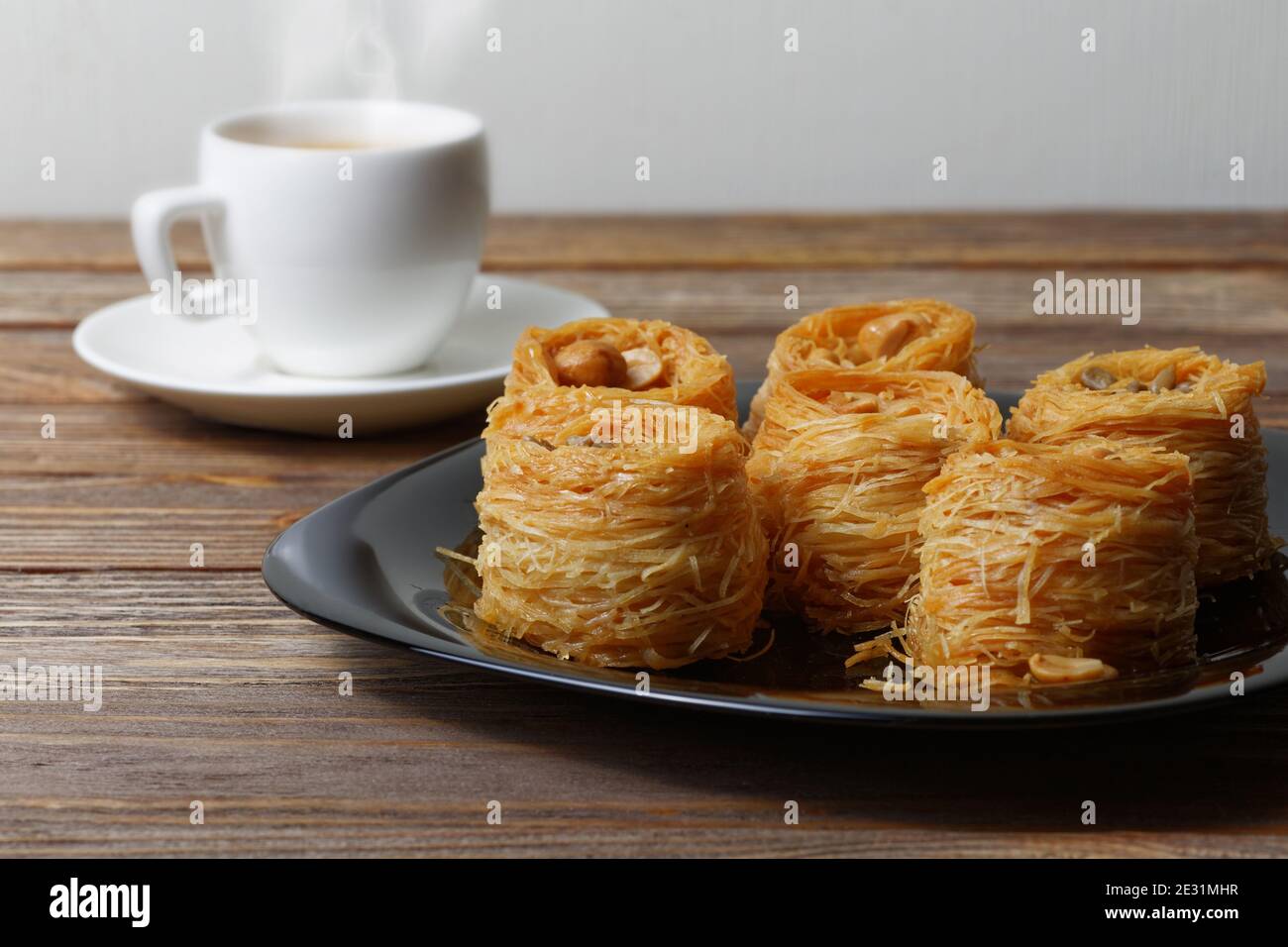 Östliche Süßigkeiten auf Holztisch und eine Tasse Kaffee auf verschwommenem Hintergrund. Geringer Fokus. Stockfoto