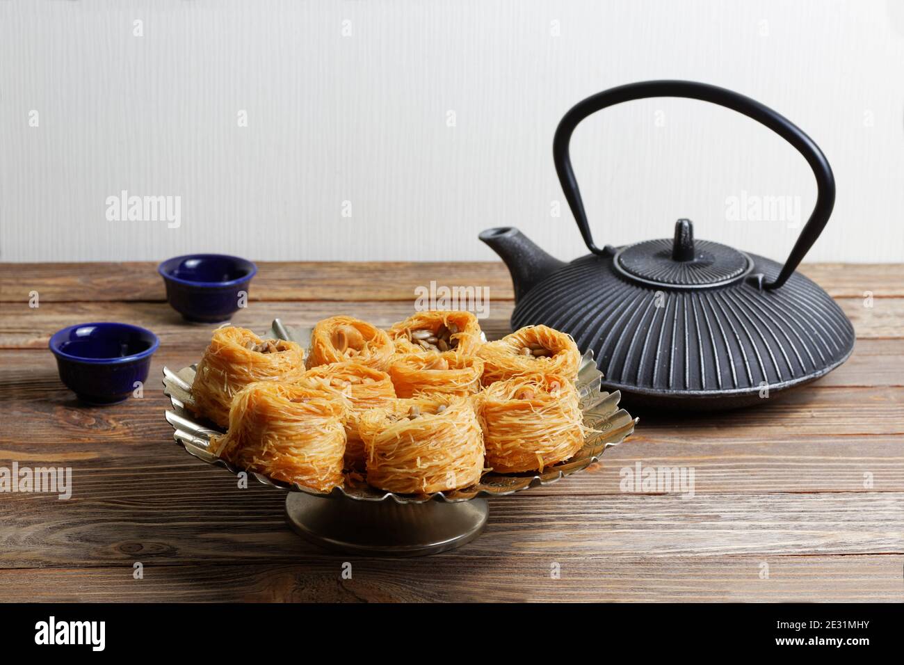 Östliche Süßigkeiten Baklava, Wasserkocher und zwei kleine Schalen auf Holztisch Stockfoto