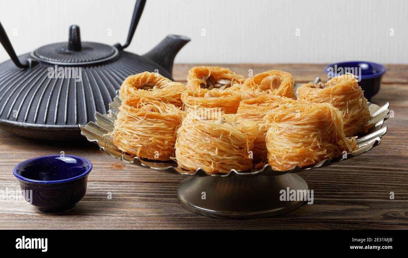 Gericht mit östlichen Süßigkeiten und Wasserkocher auf Holztisch Stockfoto