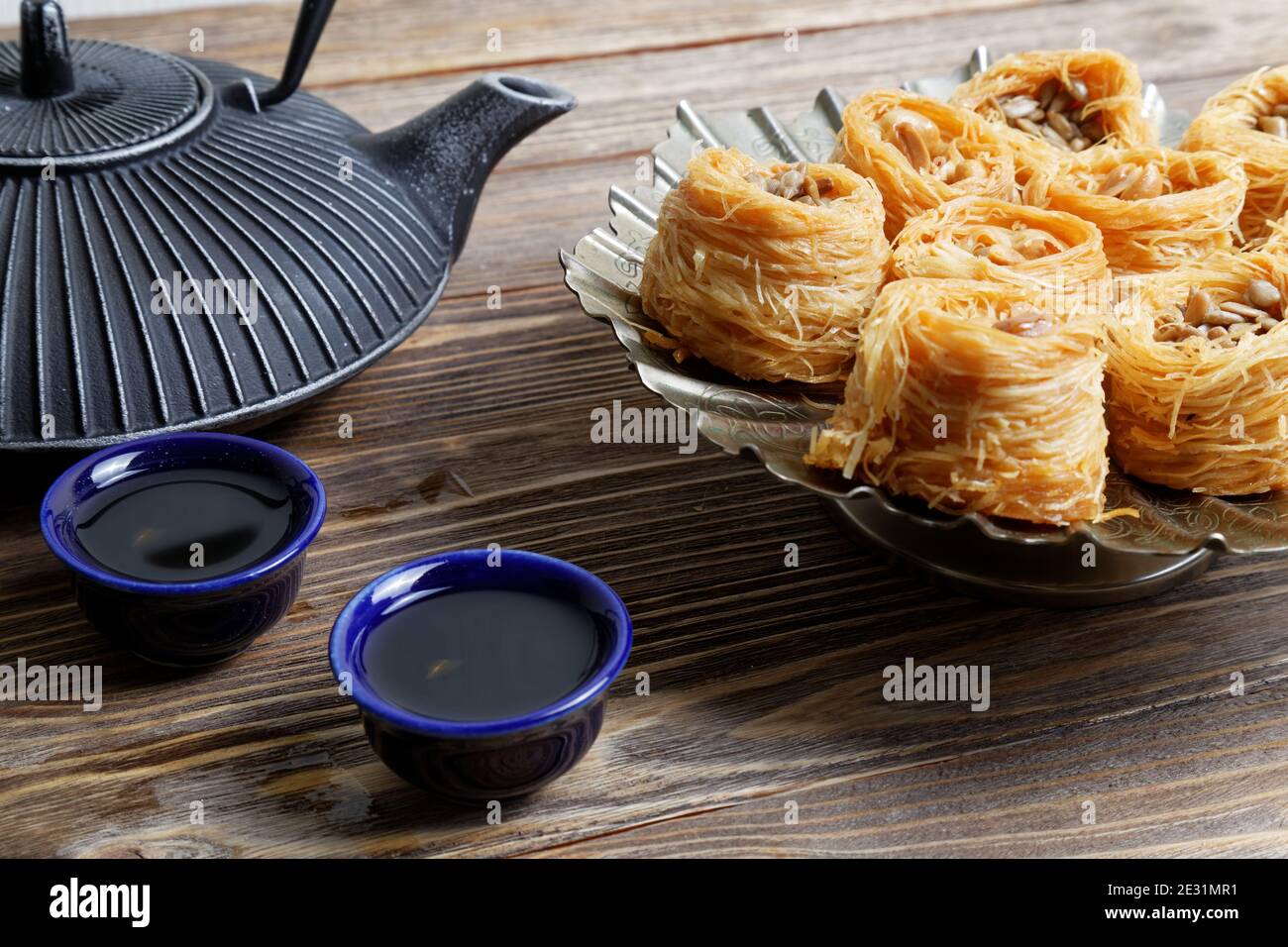 Östliche Süßigkeiten Baklava, Teekanne und zwei kleine Schüsseln auf Holztisch Stockfoto