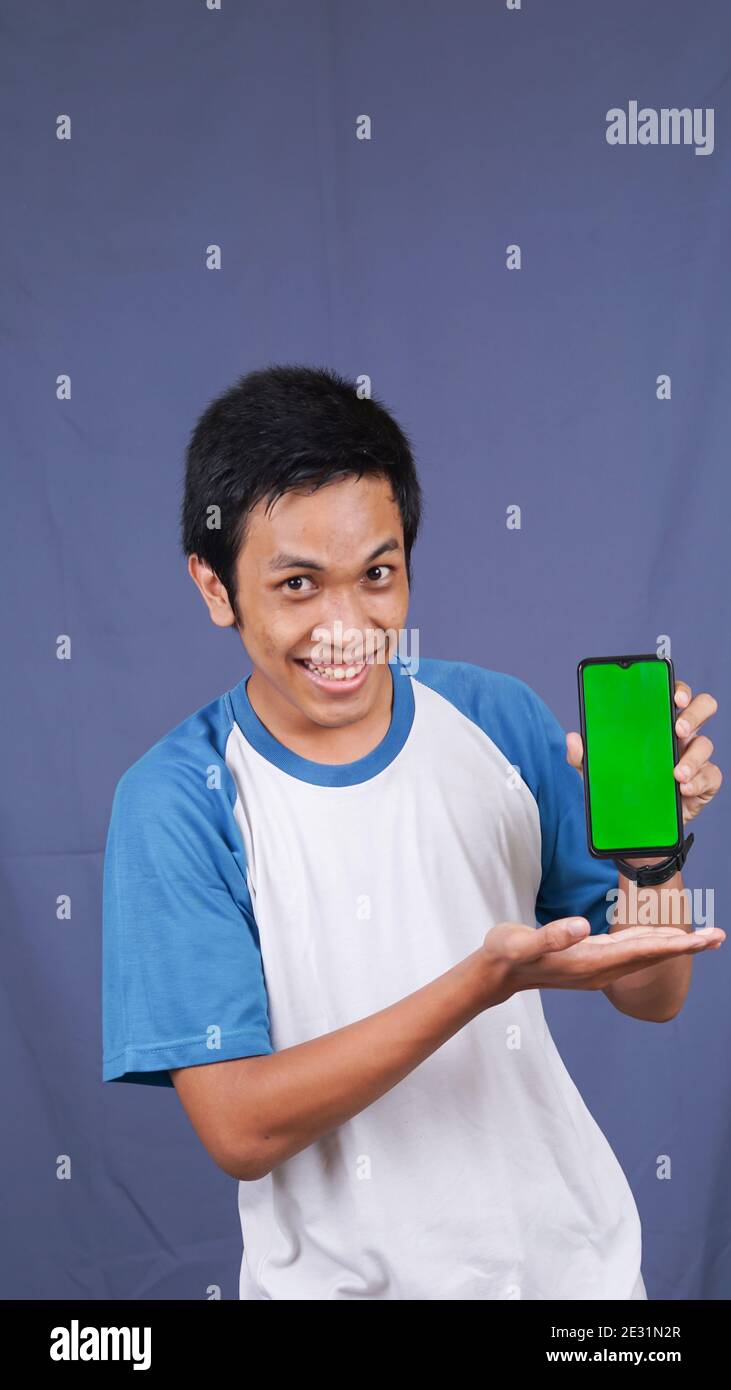 asiatischer Mann zeigt auf den grünen Bildschirm Handtelefon Stockfoto