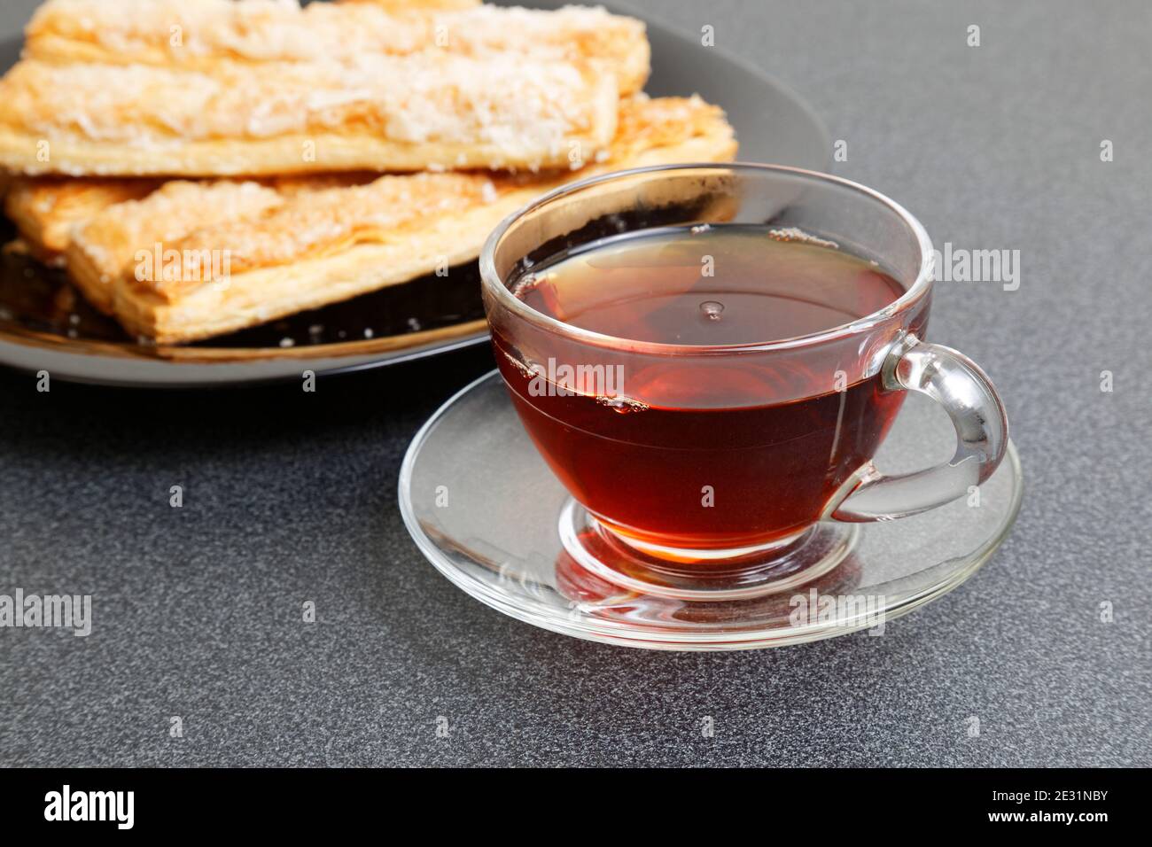 Tasse Tee und Blätterteig auf dem dunklen Tisch. Selektiver Fokus. Stockfoto