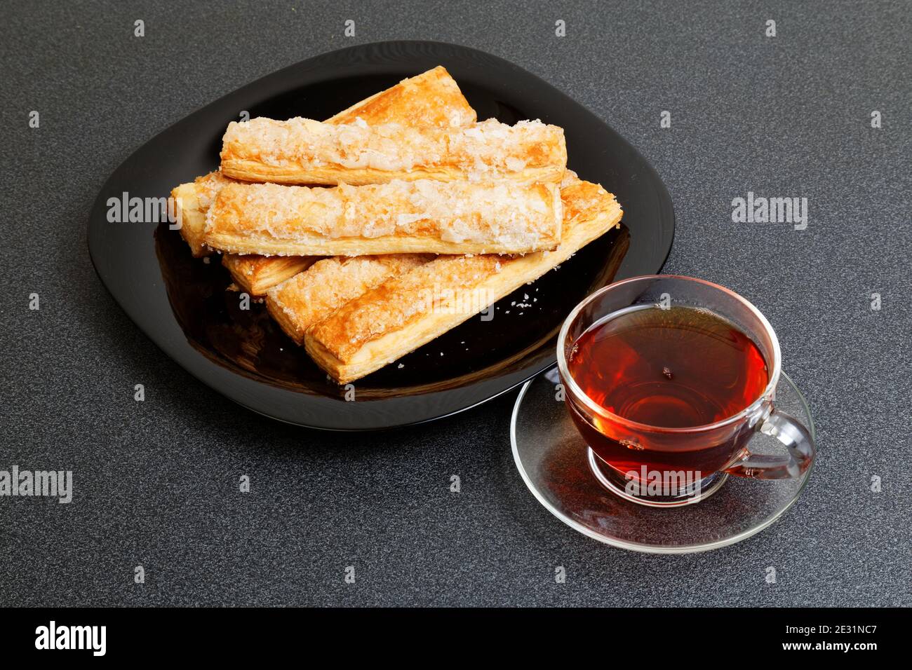 Tasse Tee und Blätterkekse auf dem dunklen Tisch Stockfoto