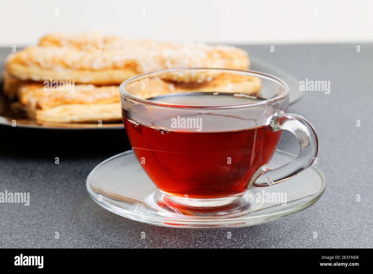 Tasse Tee und Blätterteig auf dem dunklen Tisch. Selektiver Fokus. Stockfoto