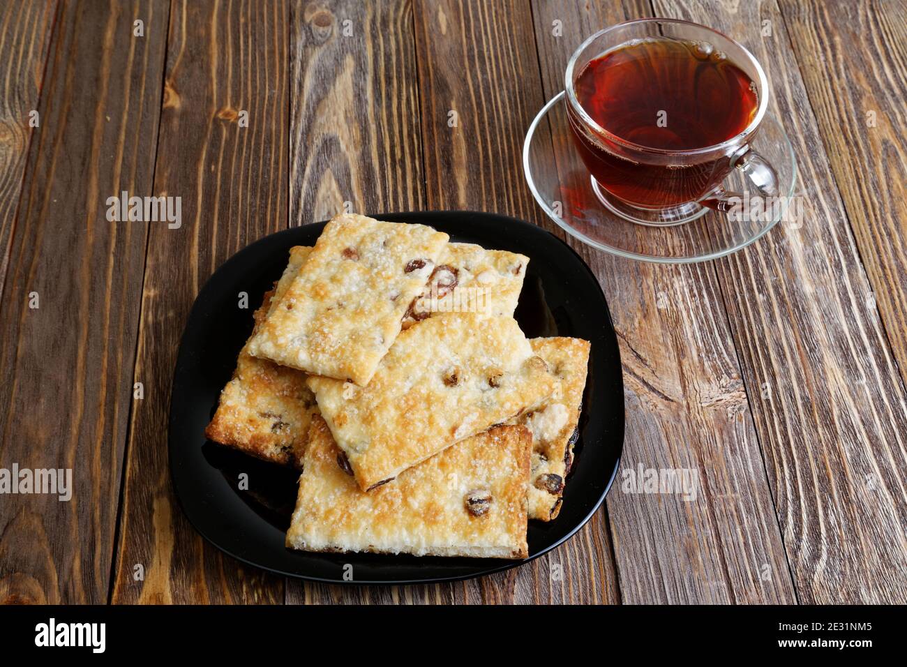 Kekse mit Rosinen und einer Tasse Tee auf dem dunkelbraunen Holztisch. Winkelansicht. Stockfoto