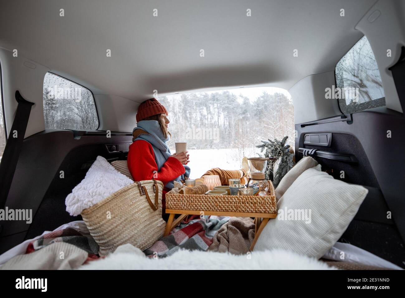 Im kofferraum des autos gibt es einen schneebedeckten weihnachtsbaum und  mandarinen auf einer blauen decke, das auto steht im winterwald