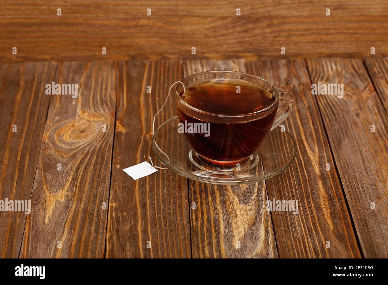 Tasse Tee auf Holztisch. Teebeutel mit weißem Etikett. Stockfoto