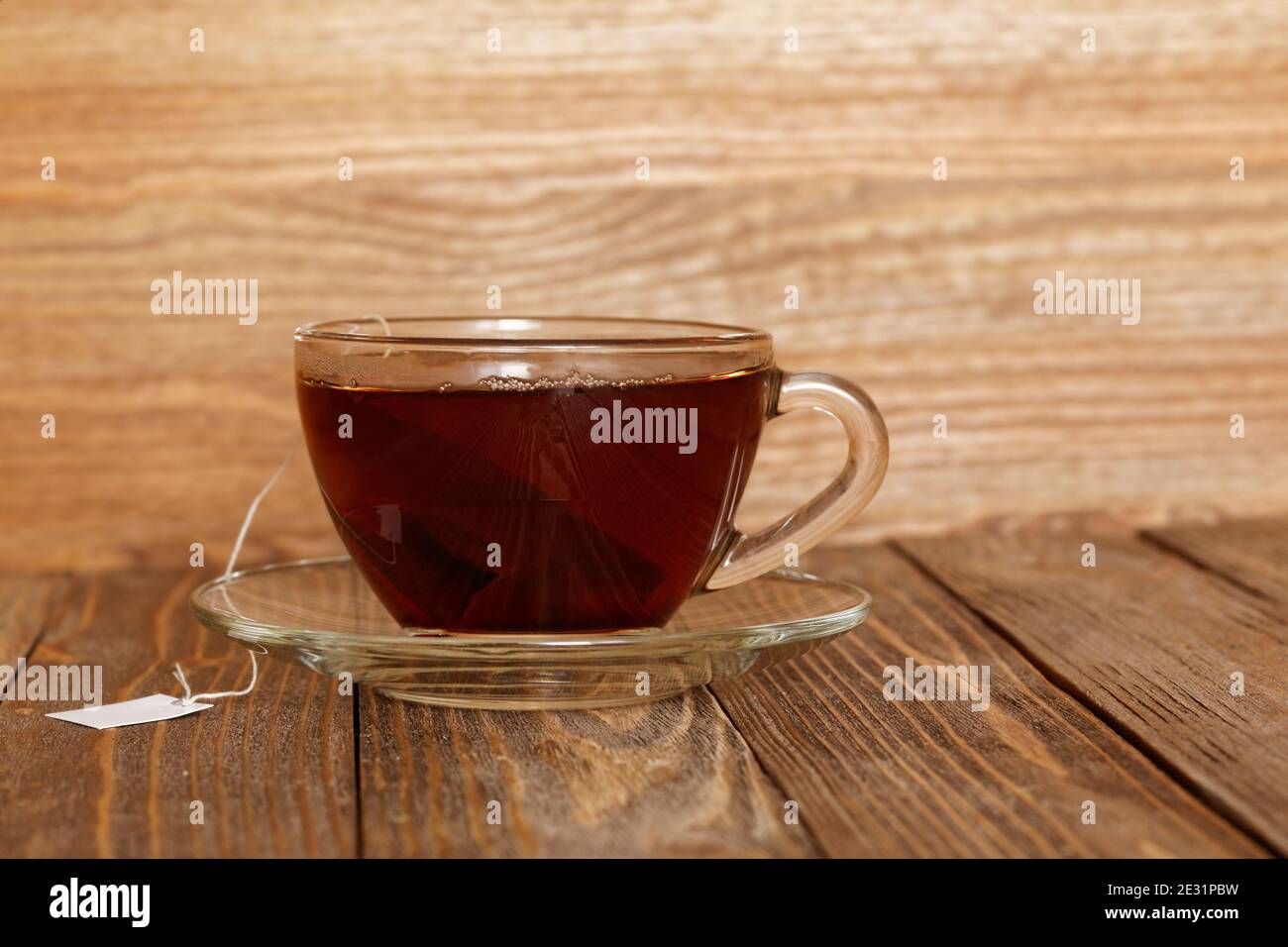 Nahaufnahme Tasse Tee auf Holztisch. Teebeutel mit weißem Etikett. Direkte Aussicht. Stockfoto