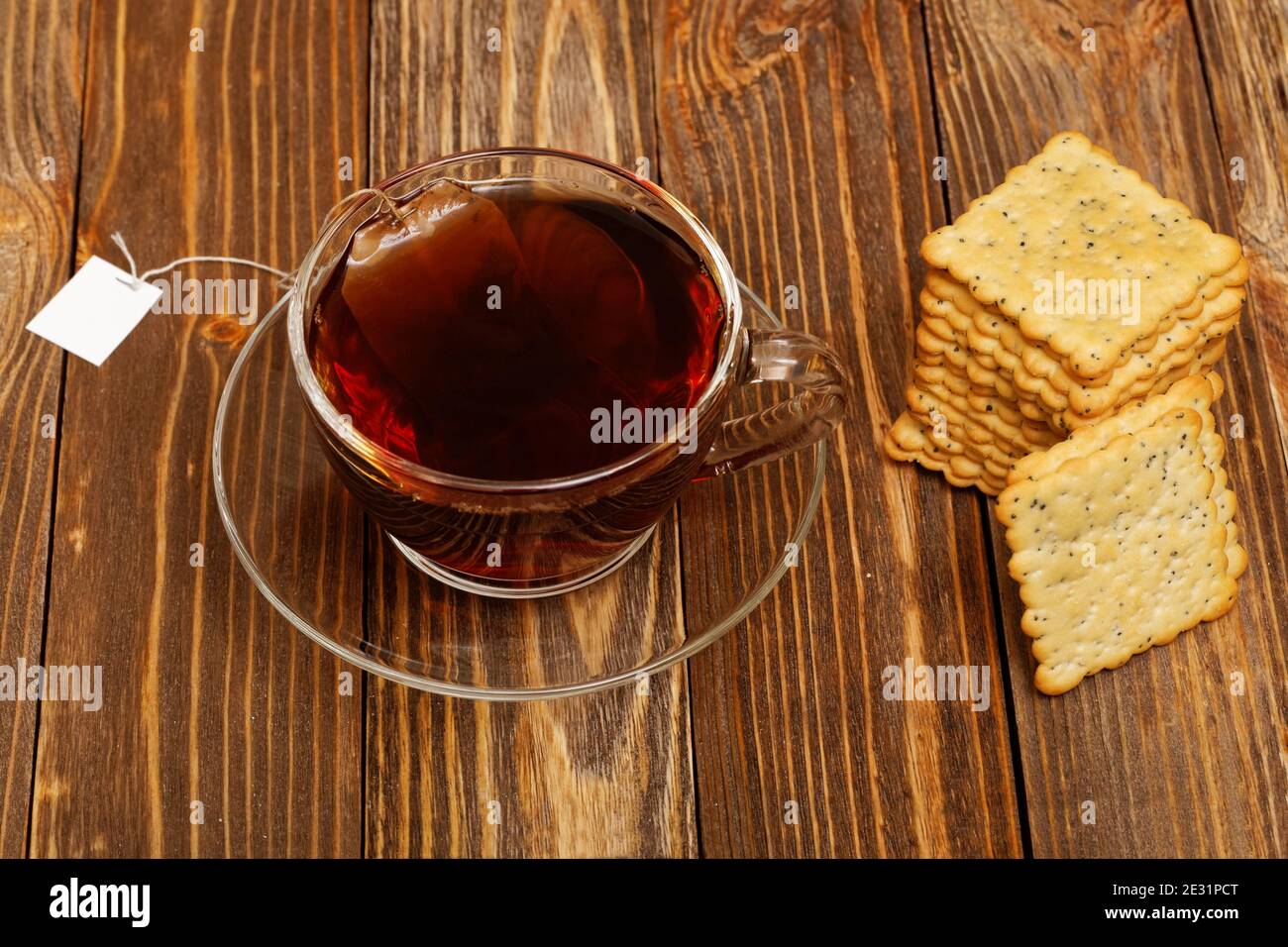 Nahaufnahme Tasse heißen Tee und Kekse auf Holztisch. Teebeutel mit weißem Etikett. Stockfoto