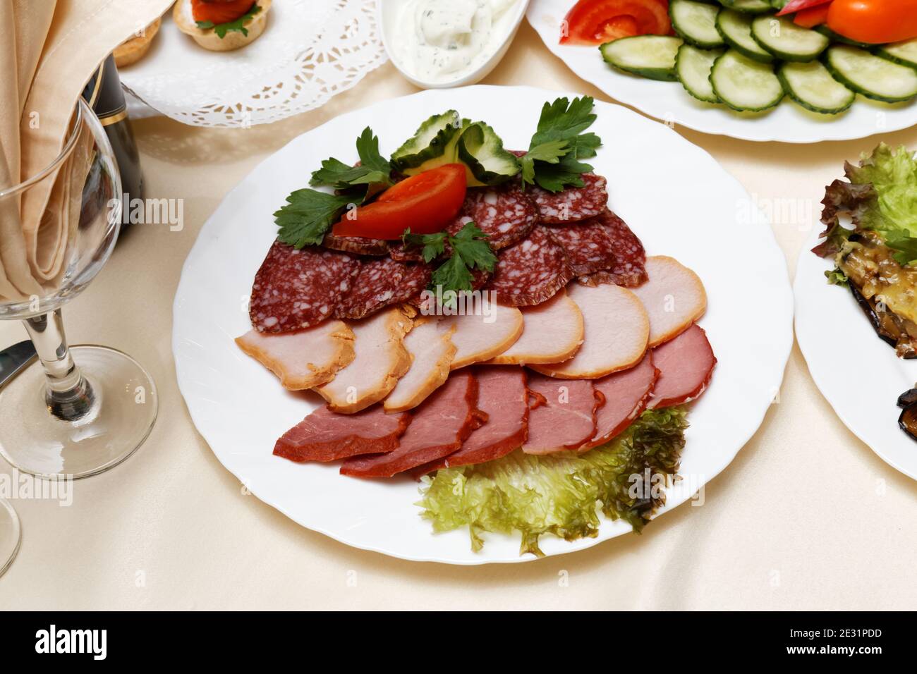 Fleisch Scheiben, Salami, Karbonat auf weißem Gericht umgeben von anderen Gerichten Stockfoto