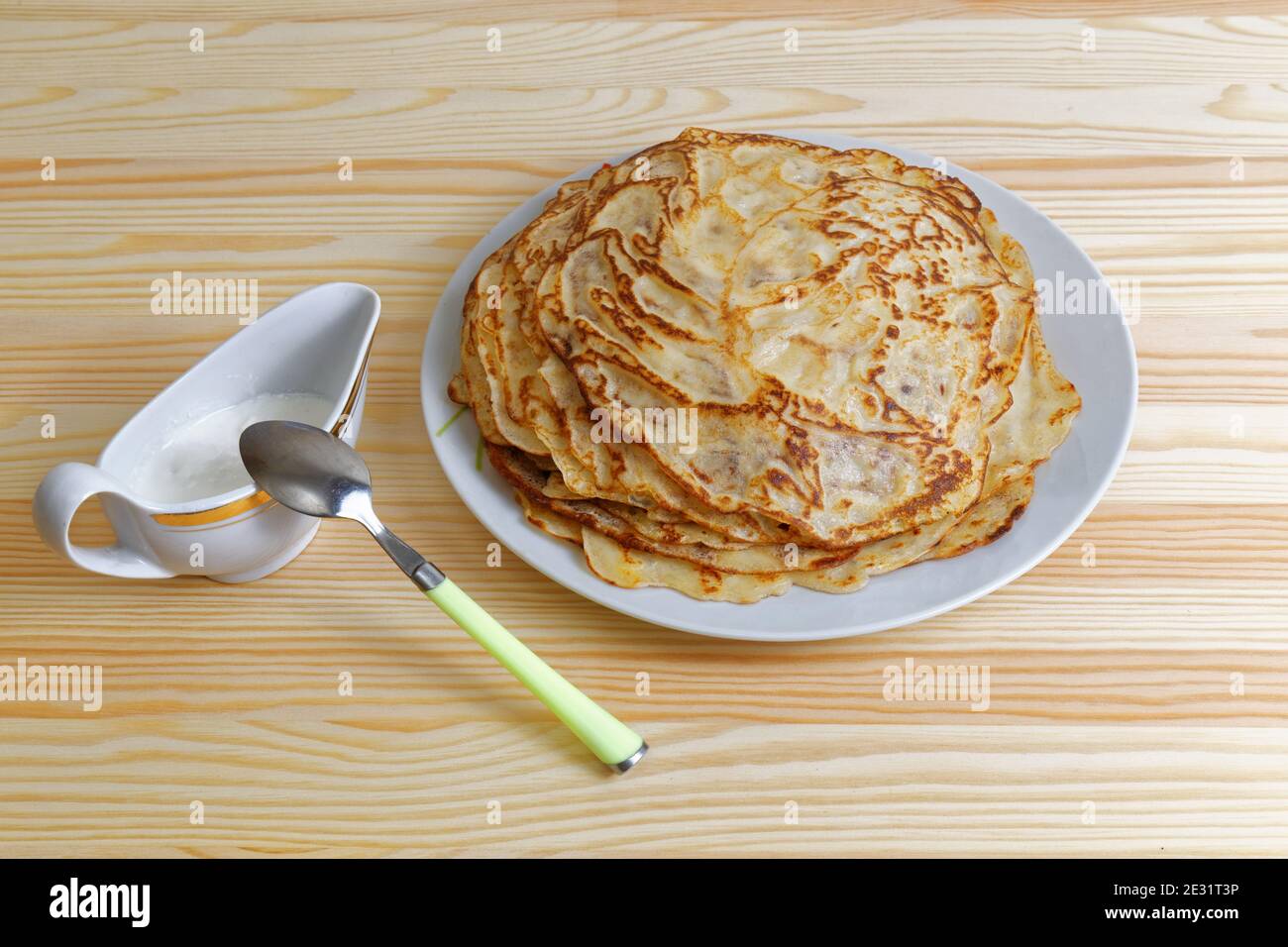 Braten Sie hausgemachte Pfannkuchen mit Sauerrahm auf einem Holztisch Stockfoto