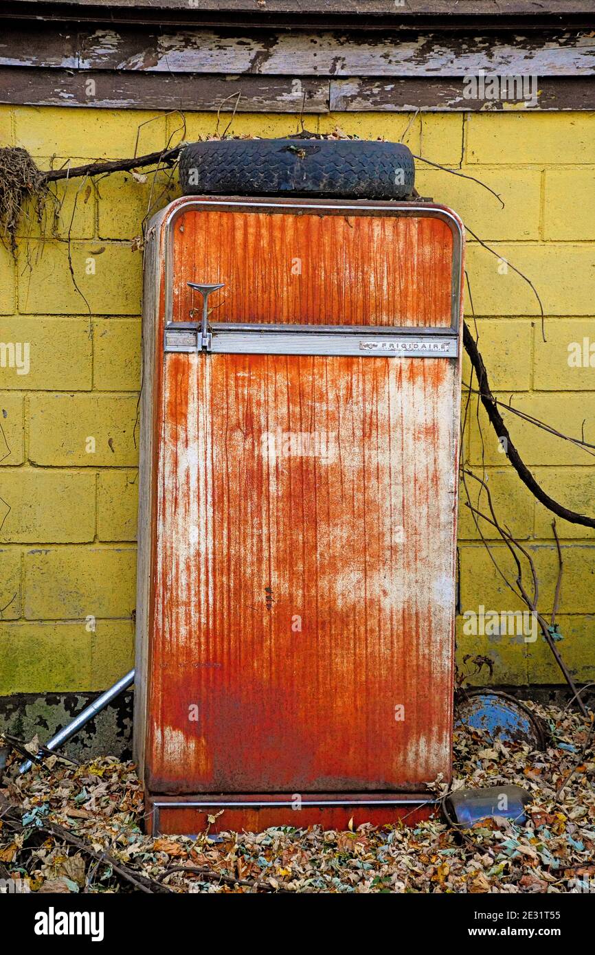 Vertikale Aufnahme eines alten rostigen Kühlschranks mit einem Rad Oben Stockfoto