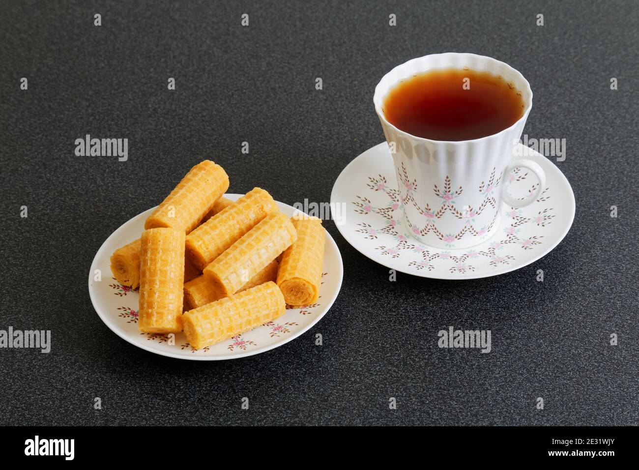 Waffer Rollen und Tasse porzellan Tee im Dunkeln Tabelle Stockfoto