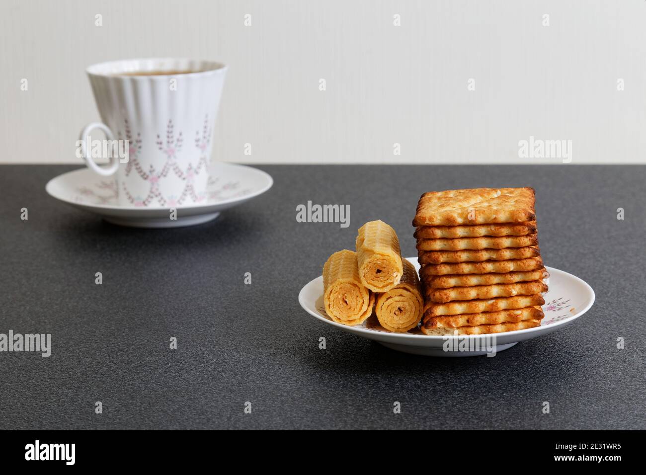 Kekse und entkochte Tasse Tee auf dem dunklen Tisch Stockfoto