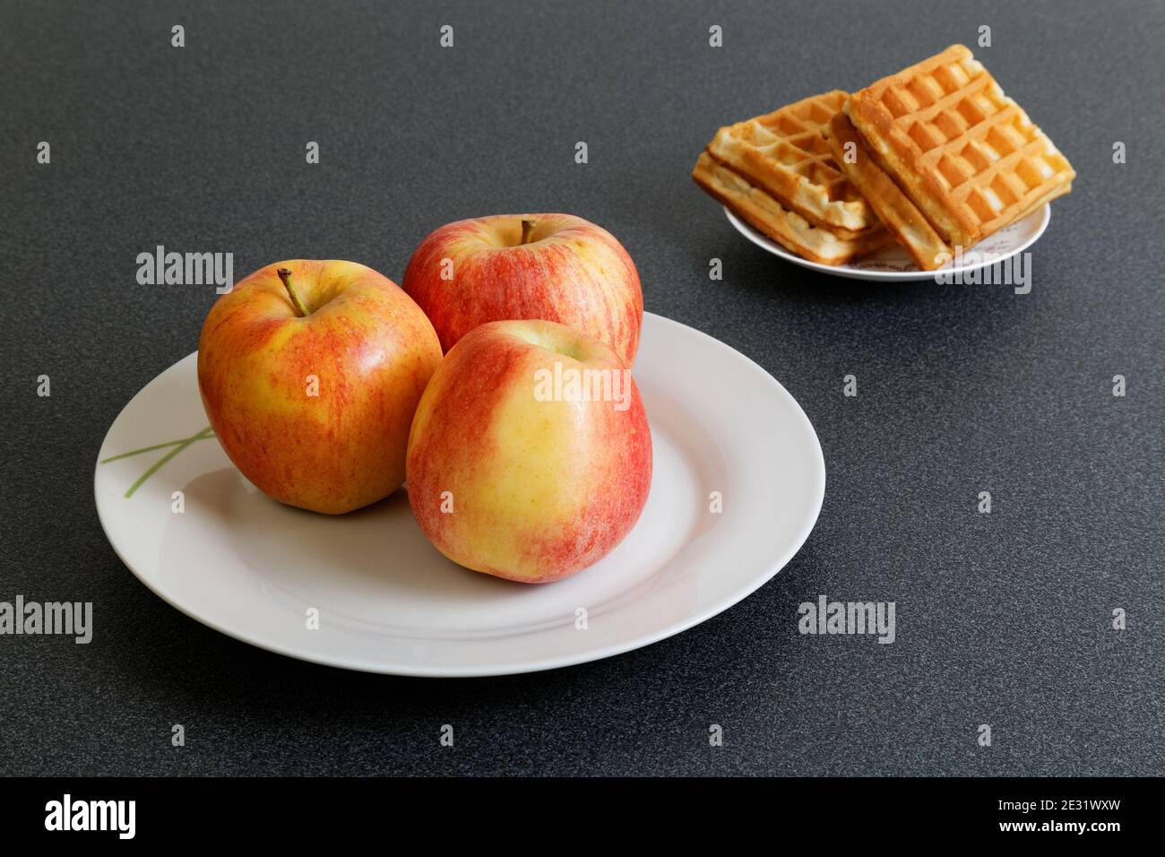 Äpfel und Kekse auf dunklem Tisch. Treffen Sie Ihre Wahl. Stockfoto