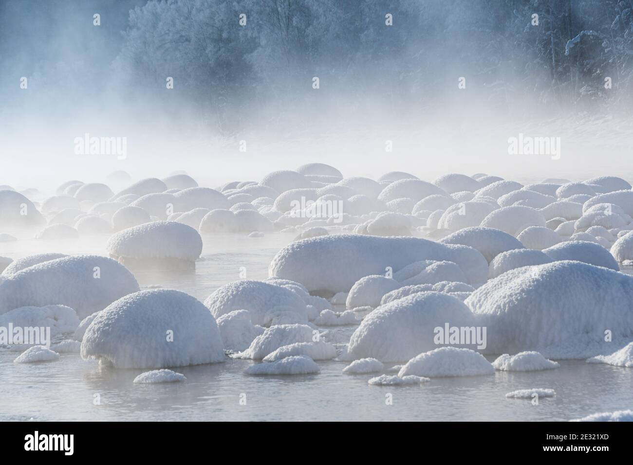 Winterlandschaft des Sees mit nebliger Oberfläche. Felsen und Bäume am Flussufer sind mit Schnee bedeckt. Stockfoto