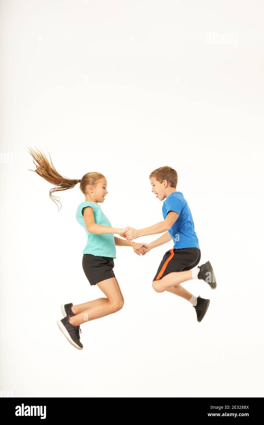 Cute boy in Sportswear unter die Hände von charmanten Mädchen beim Springen in die Luft. Isoliert auf weißem Hintergrund Stockfoto