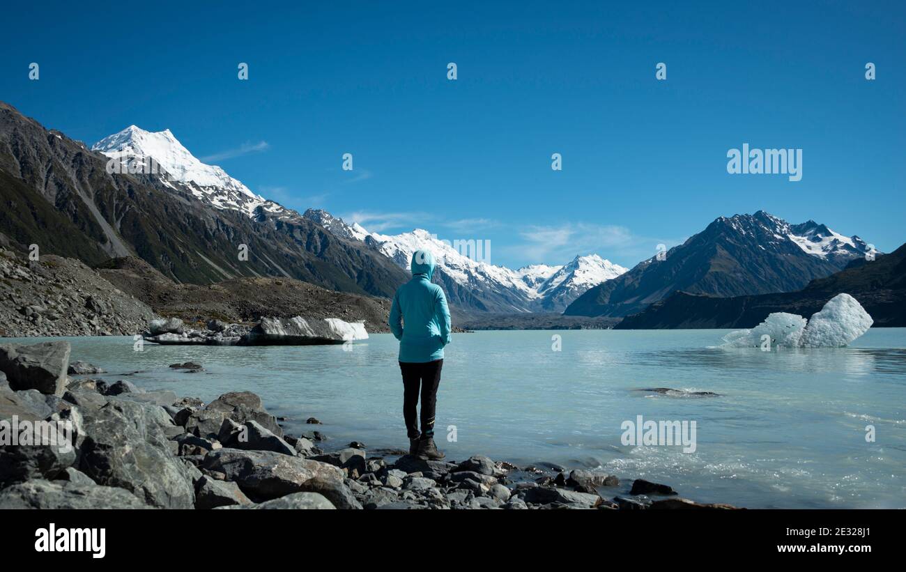 Touristen stehen am Ufer des Tasman Glacier Terminal Lake Blick auf schneebedeckte Berge und Eisberge Stockfoto
