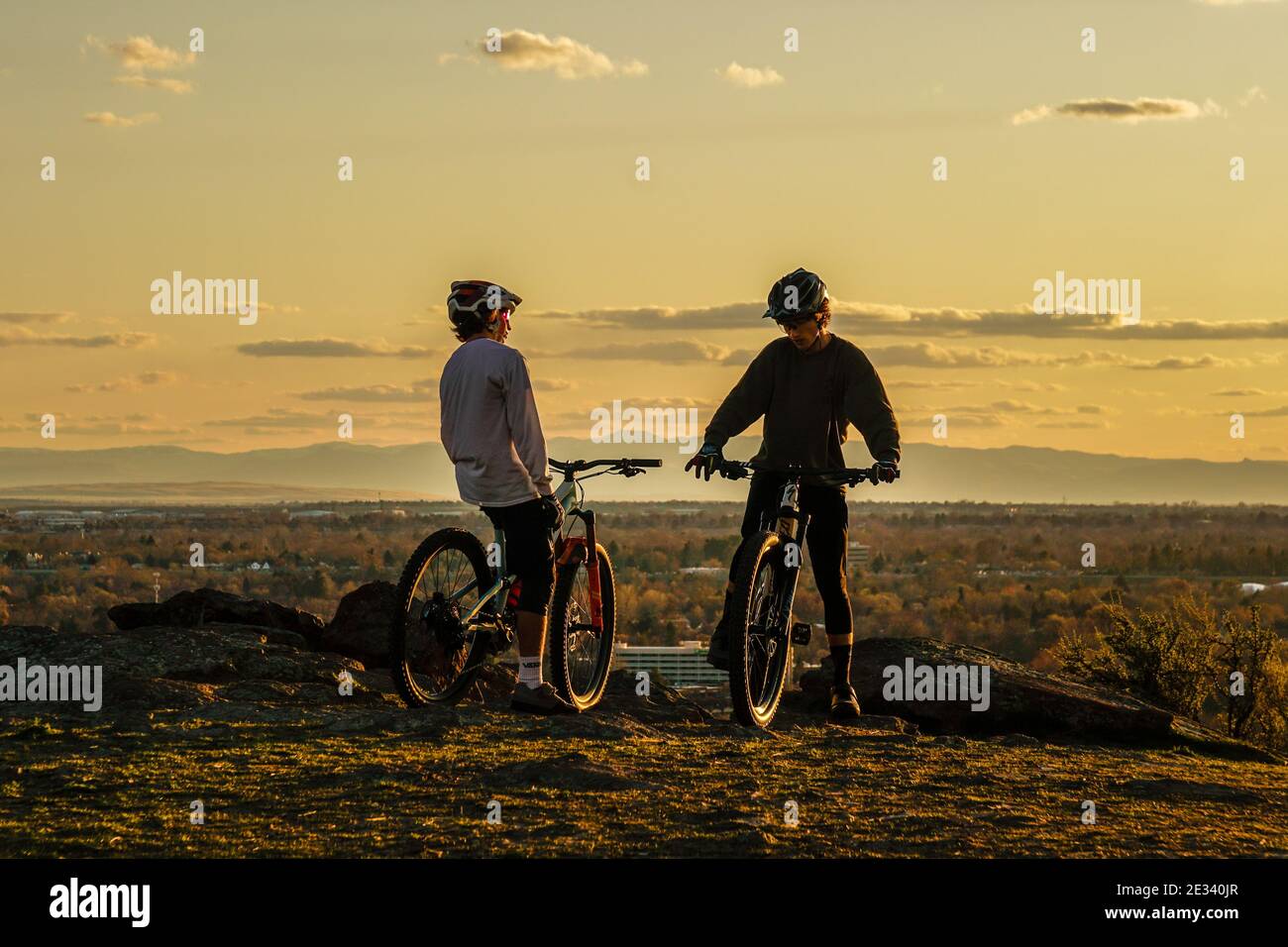 Zwei Mountainbike-Fahrer auf Castle Rock bei Sonnenuntergang über der Stadt Boise, Idaho. Stockfoto