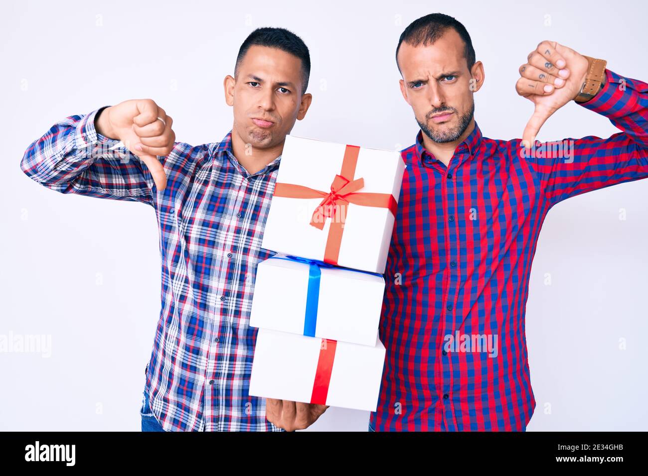 Junge Homosexuell paar von zwei Männern halten Geschenk mit wütenden Gesicht, negative Zeichen zeigt Abneigung mit Daumen nach unten, Ablehnung Konzept Stockfoto