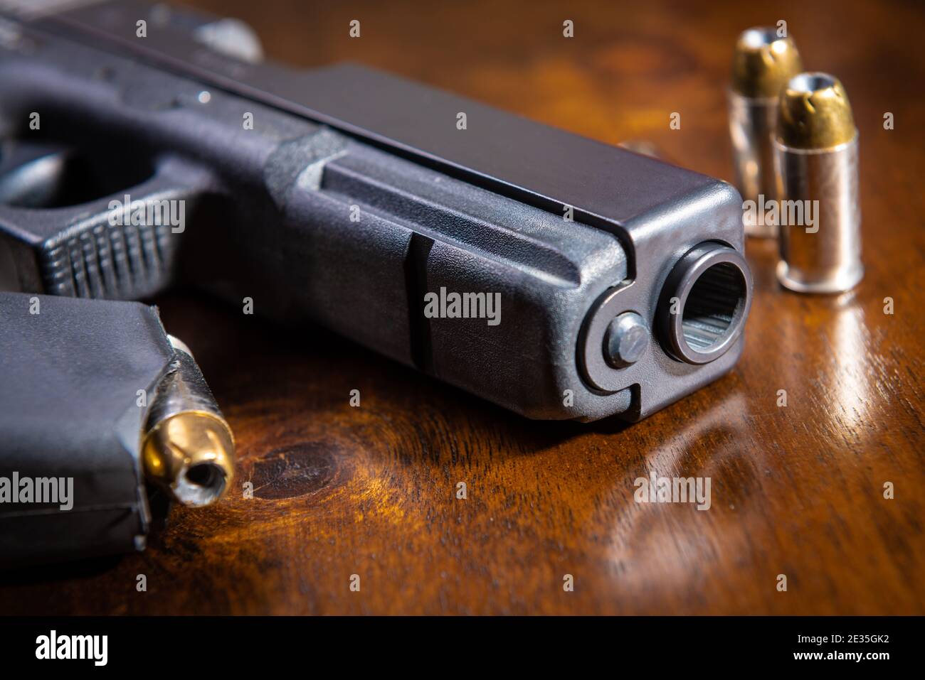 Eine schwarze halbautomatische Pistole und Munition auf einem Holztisch. Stockfoto