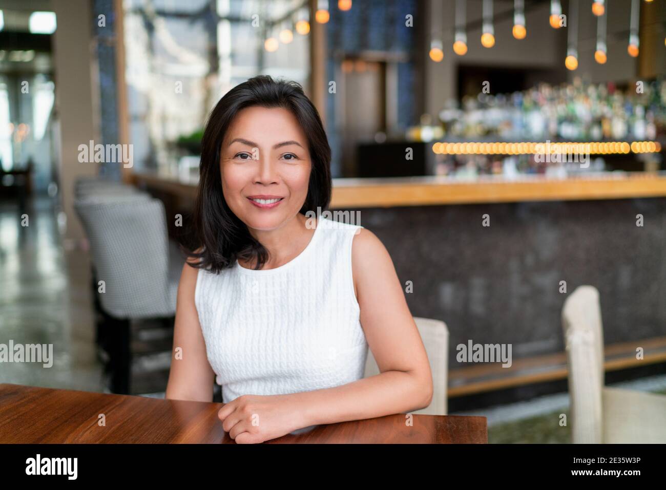 Asiatische mittleren Alters Geschäftsfrau lächelnd Porträt. Glückliche elegante reife chinesische Geschäftsfrau Dame in schickem Restaurant Einstellung Stockfoto