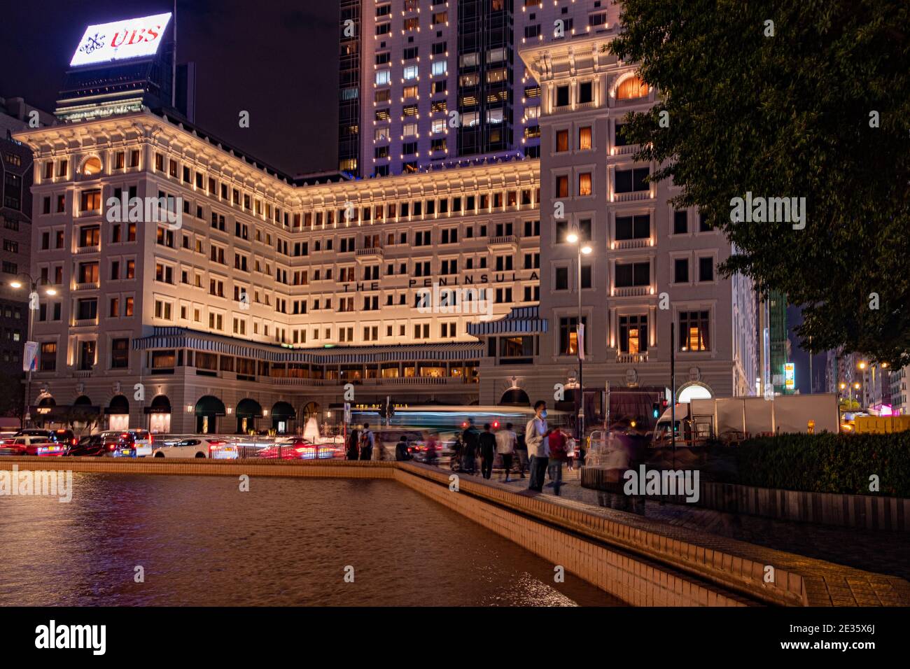 Wenn der Abend über dem Peninsula Hotel fällt, reflektiert das sanfte Leuchten der Lichter der Stadt vom Brunnen. Stockfoto