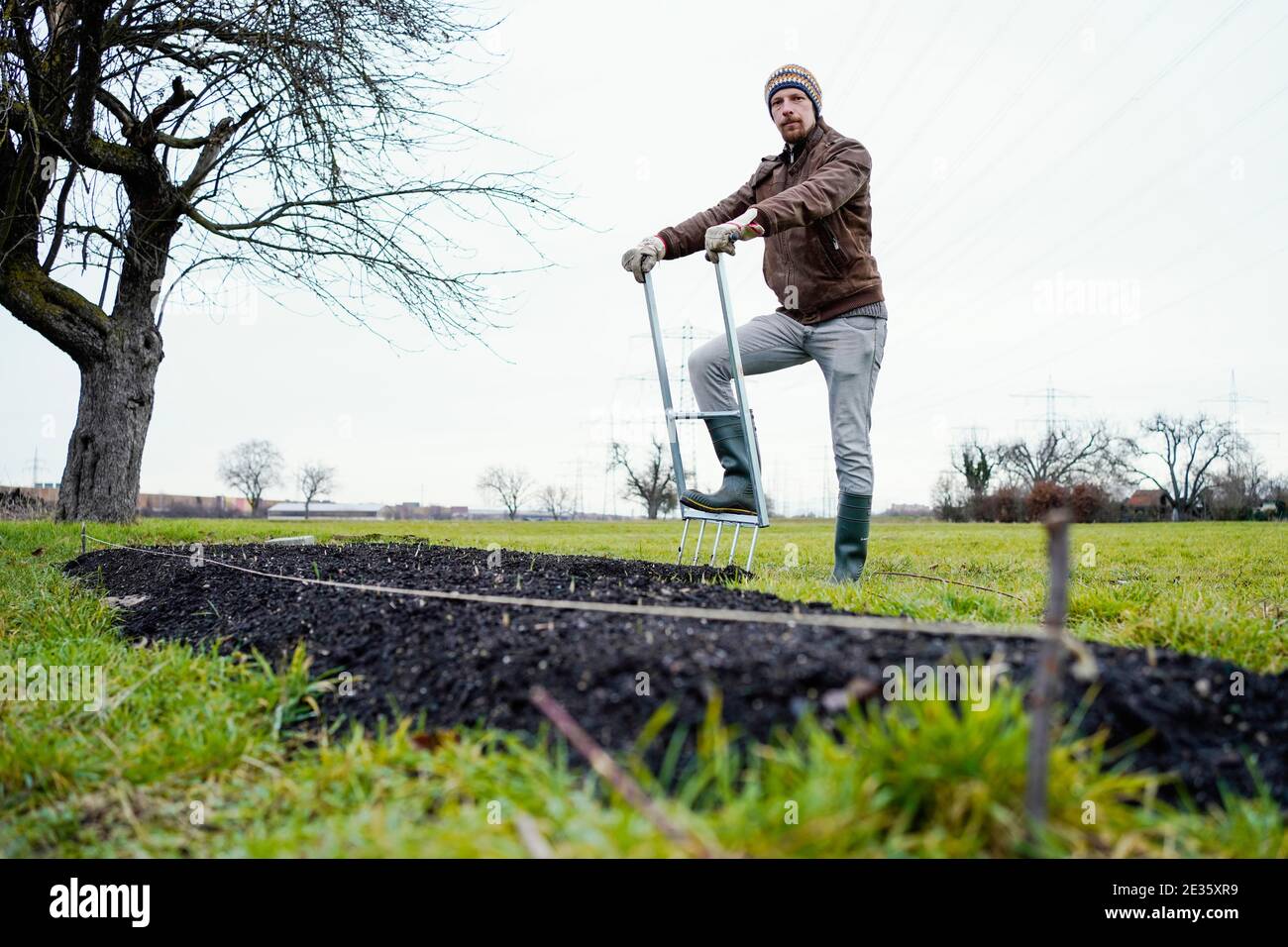 Mannheim, Deutschland. Januar 2021. Johannes Stange, Jazztrompeter und angehende Bio-Bauer, steht an einem Bett aus Knoblauchpflanzen. Angesichts der Absage von Konzerten aufgrund von Corona änderte er seine Karriere und schuf mit dem Gartenbau eine zweite wirtschaftliche Säule. (An dpa-KORR: 'Keine Konzerte: Musiker schaffen zweite Stütze bei Gärtnern') Quelle: Uwe Anspach/dpa/Alamy Live News Stockfoto