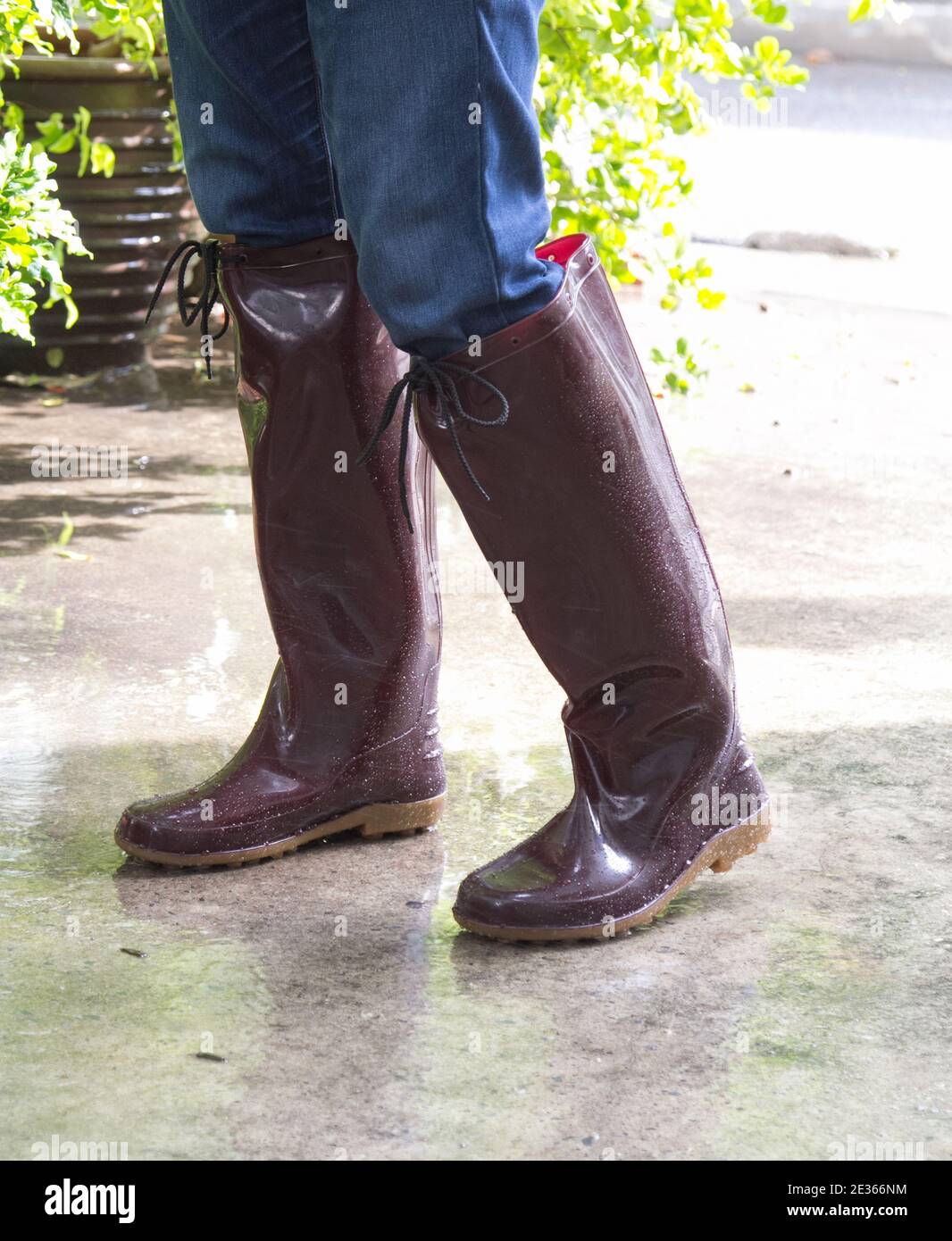 Mann in braunen Gummistiefeln auf nassem Boden nach Regen. Stockfoto