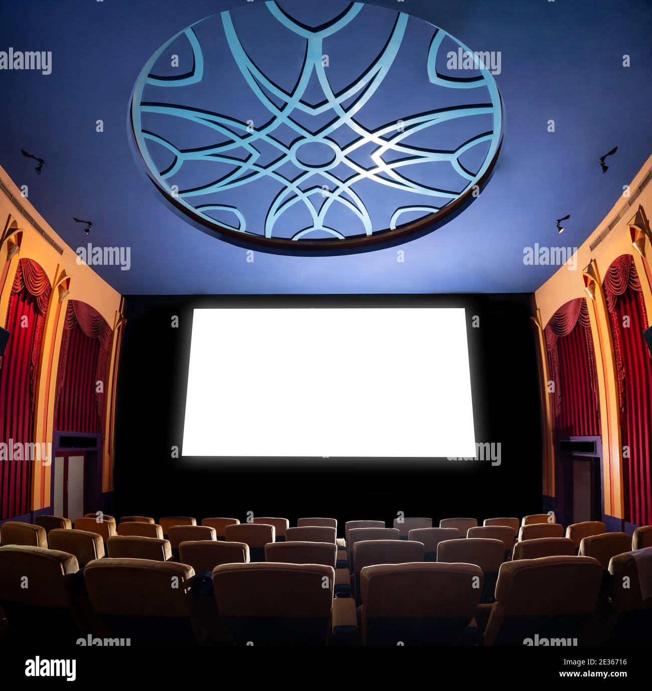 Kinoleinwand vor den Sitzreihen im Kino, auf der die weiße Leinwand vom Kinematographen projiziert wird. Das Kino ist eingerichtet Stockfoto
