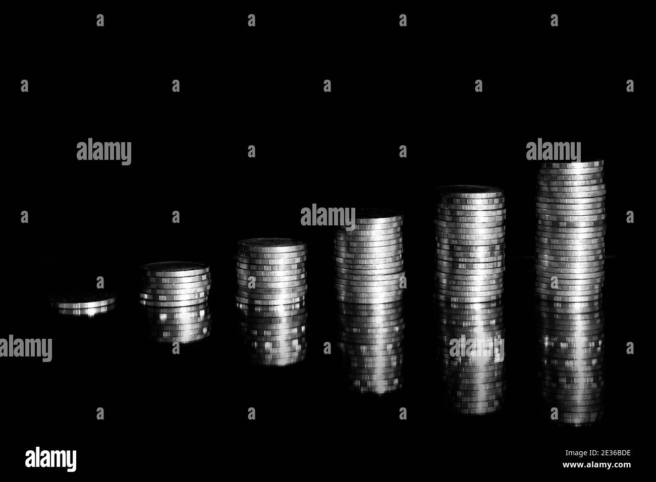 Wachsende Geldgraph auf einer Reihe von Münzen und Haufen von Baht Münzen Stapel isoliert auf schwarzem Hintergrund. Finanzgeschäft. Stockfoto