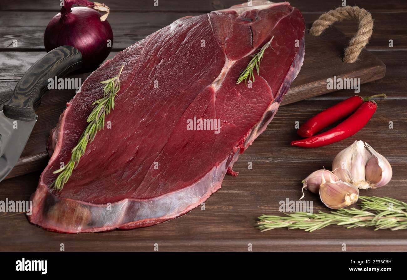 Stück frisches rohes Fleisch auf Holzhintergrund. Fleisch und Gewürze. Stockfoto