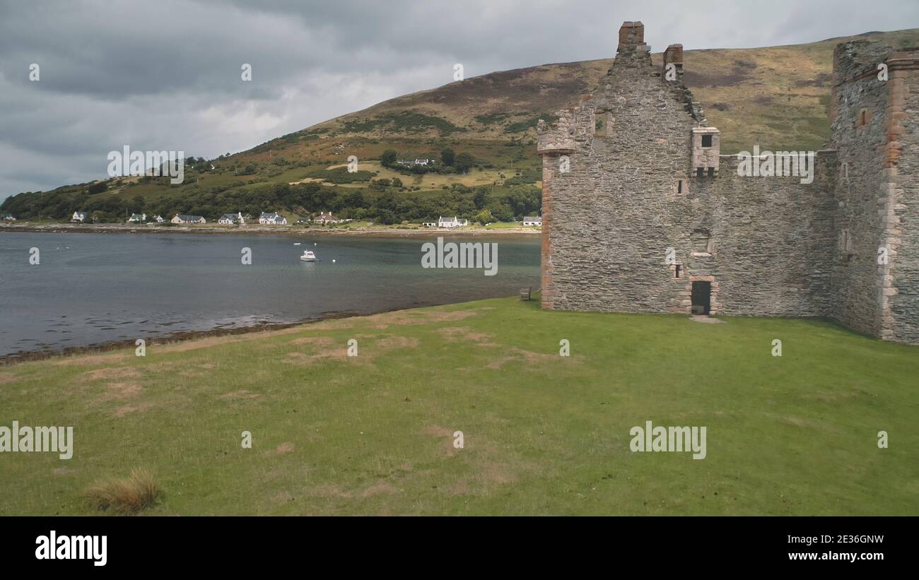 Closeup Burgmauern Ruinen an Seeslandschaft Luft. Historischer britischer Palast der Hamilton-Dynastie. Green Grass Valley and Mountain an der Küste von Loch-Ranza, Arran Island, Schottland, Vereinigtes Königreich, Europa Stockfoto