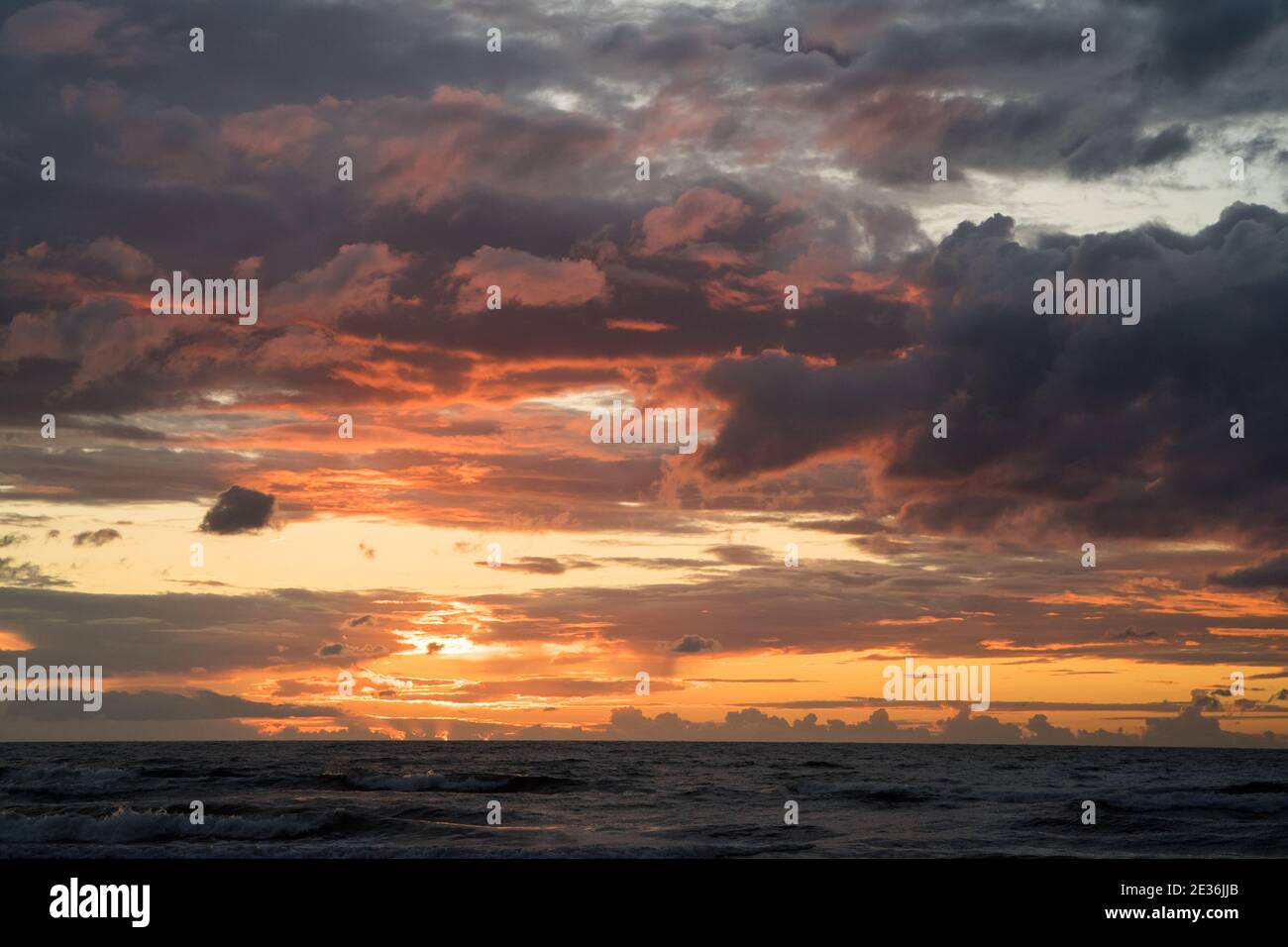Schönes warmes Sonnenuntergangslicht in den Wolken über der ostsee Horizontal Stockfoto