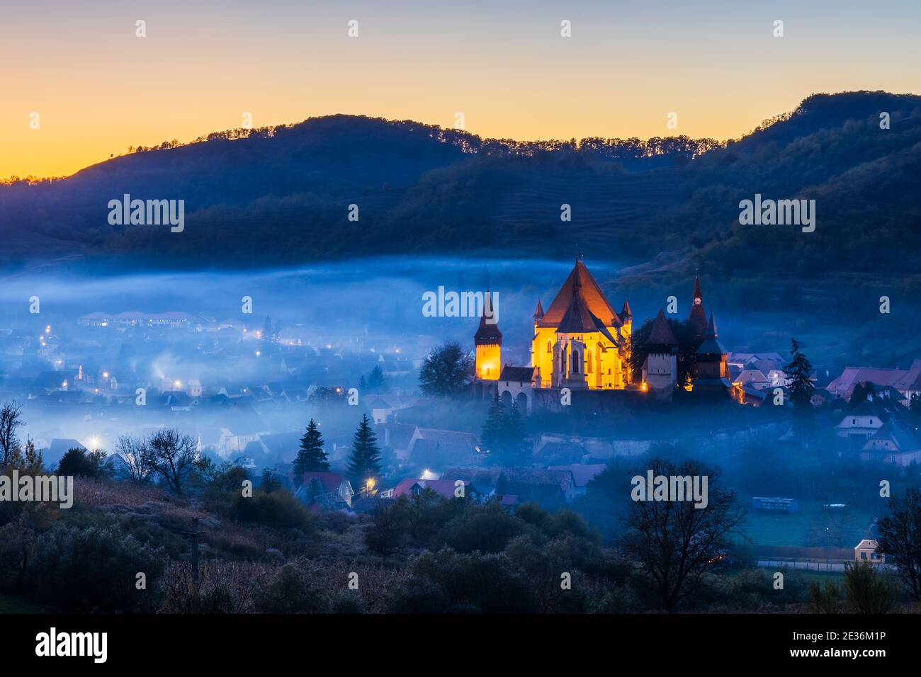 Biertan, Rumänien. Nebliger Sonnenuntergang im sächsischen Dorf mit der befestigten Kirche, Siebenbürgen. Stockfoto
