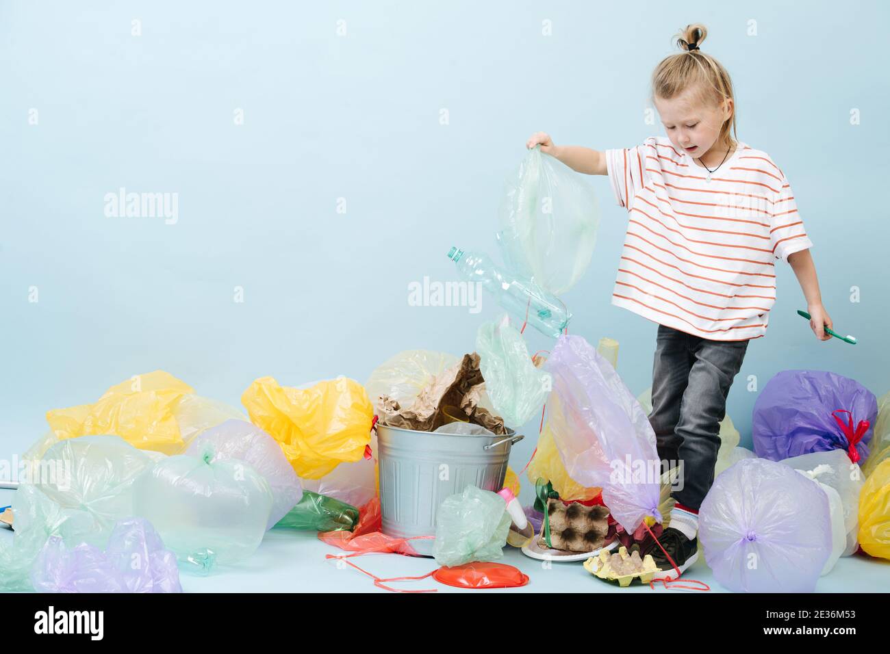 Junge Öko-Aktivist sortiert Müll auf blauem Hintergrund Stockfoto