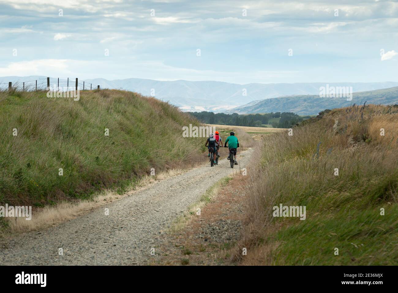 Touristen radeln den Otago Central Rail Trail mit den Bergen in der Ferne, Südinsel, Neuseeland Stockfoto