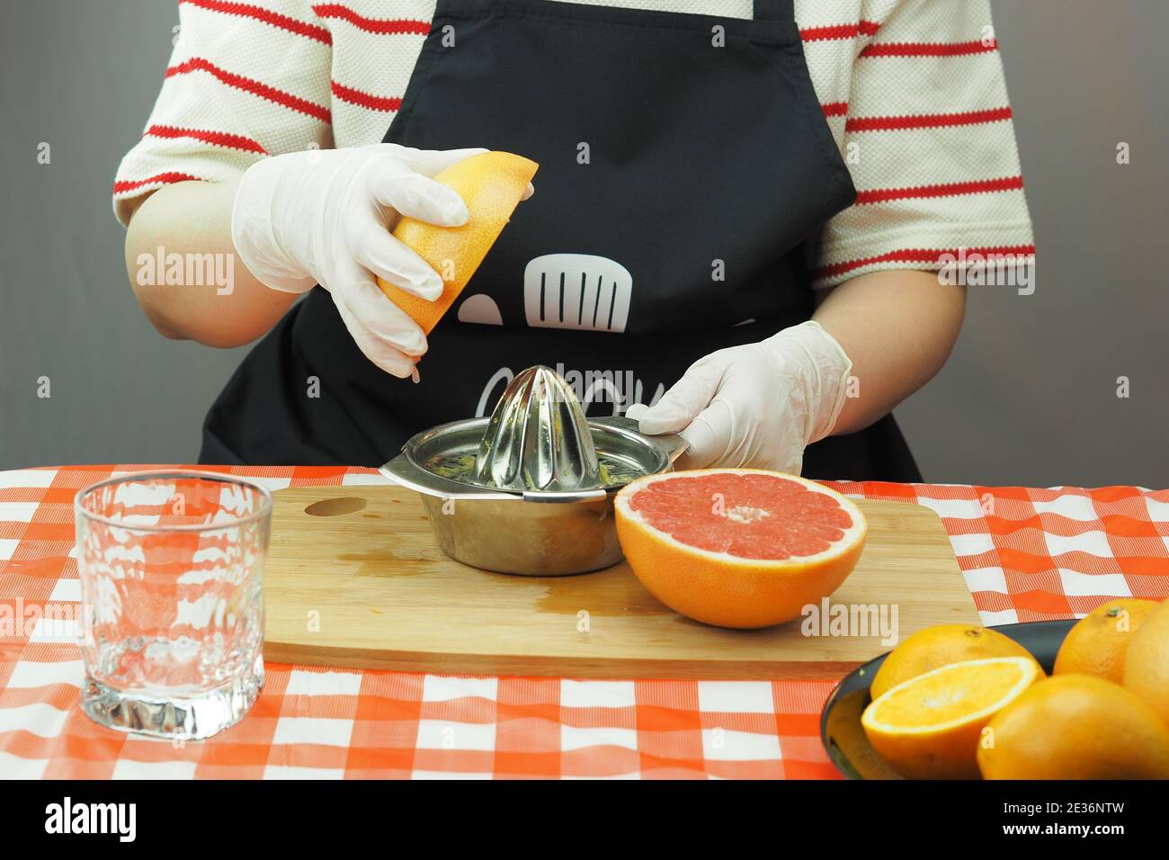 Eine junge Frau macht aus Orangen und Grapefruit auf einem handgemachten Entsafter frisch gepressten Saft. Stockfoto