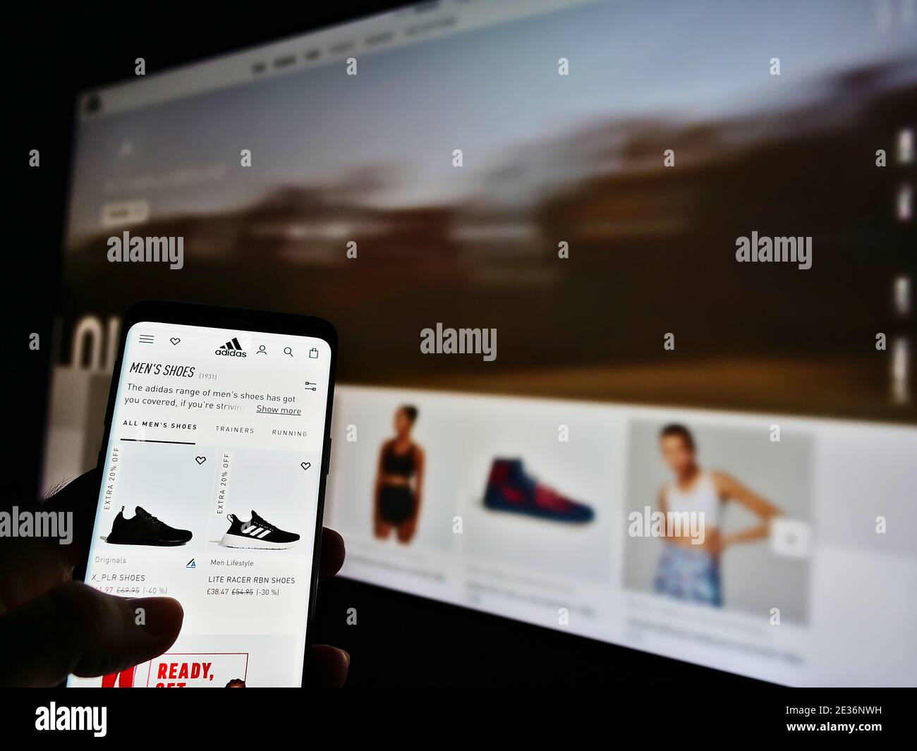 Person scrollt durch den Online-Shop des deutschen Sportartikelherstellers Adidas (Schuhe, Bekleidung, Accessoires). Konzentrieren Sie sich auf den Bildschirm des Mobiltelefons. Stockfoto