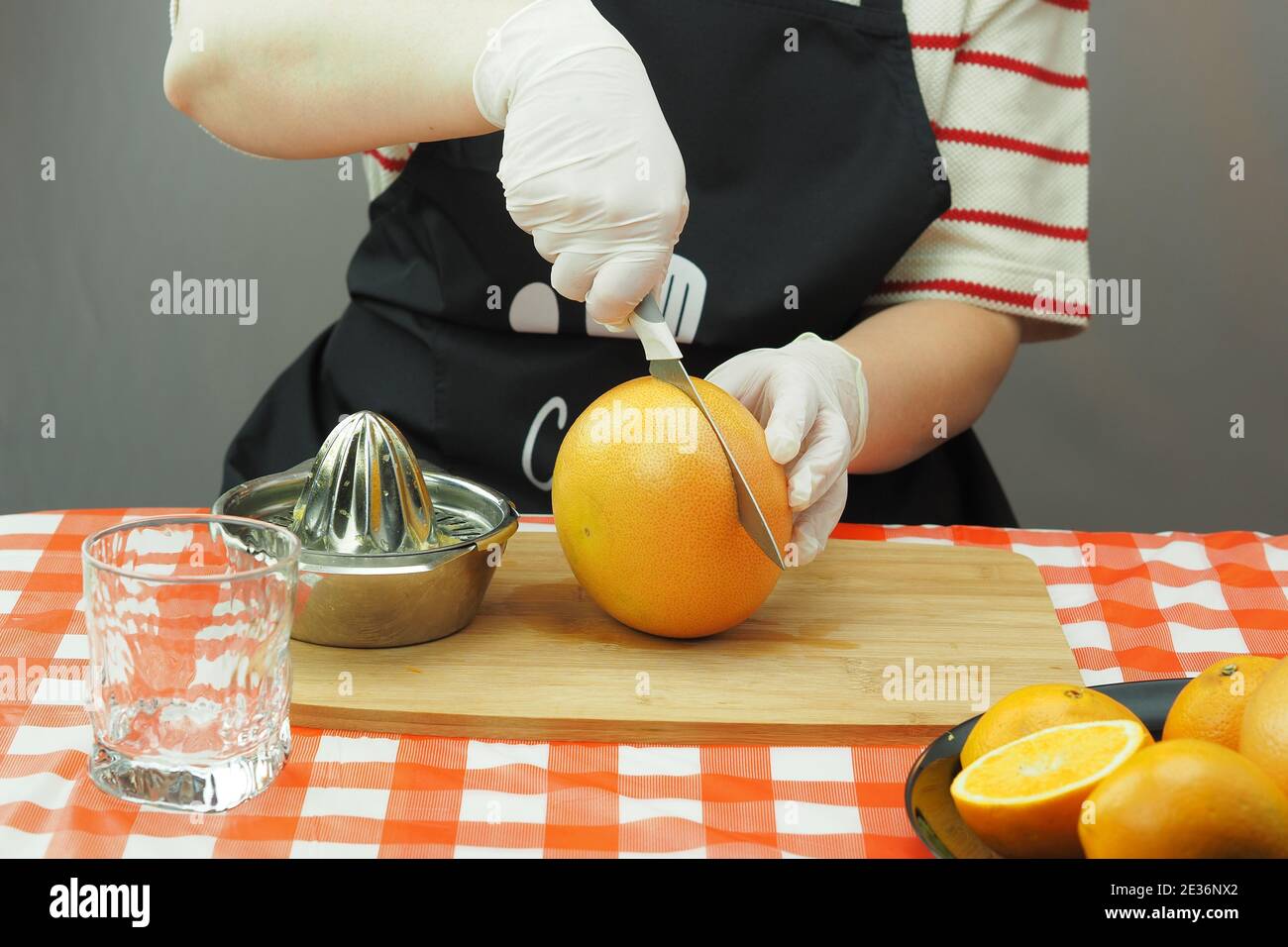 Eine junge Frau macht aus Orangen und Grapefruit auf einem handgemachten Entsafter frisch gepressten Saft. Stockfoto