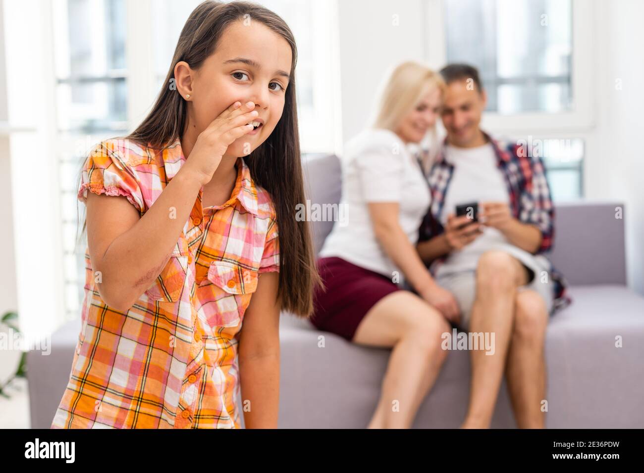 Trauriges Mädchen, das ihre Eltern hört, während es auf dem Sofa sitzt Zu Hause Stockfoto