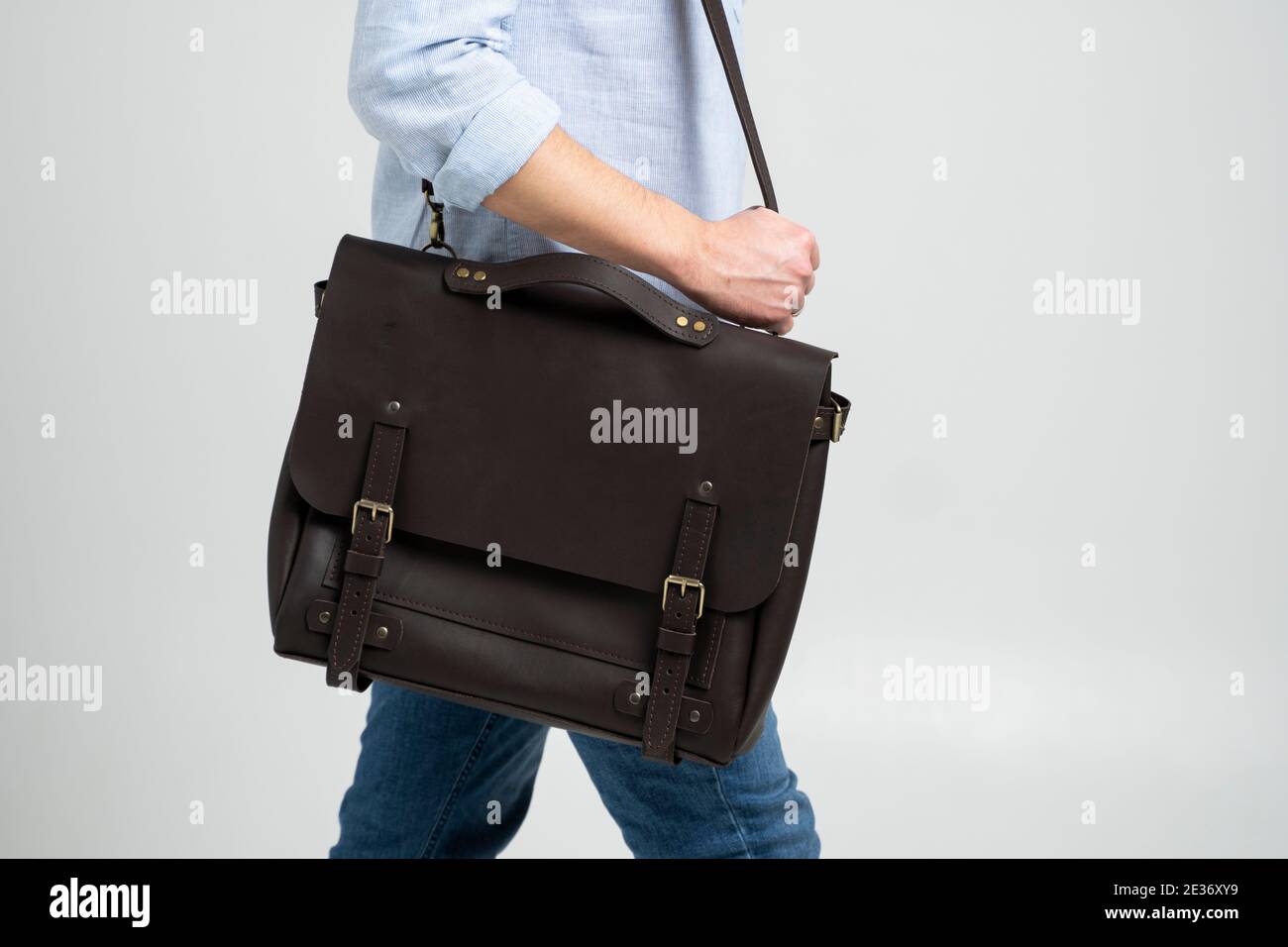 Braune Männer Schulterledertasche für Dokumente und Laptop auf den  Schultern eines Mannes in einem blauen Hemd und Jeans mit weißem  Hintergrund. Umhängetasche, Herren Stockfotografie - Alamy