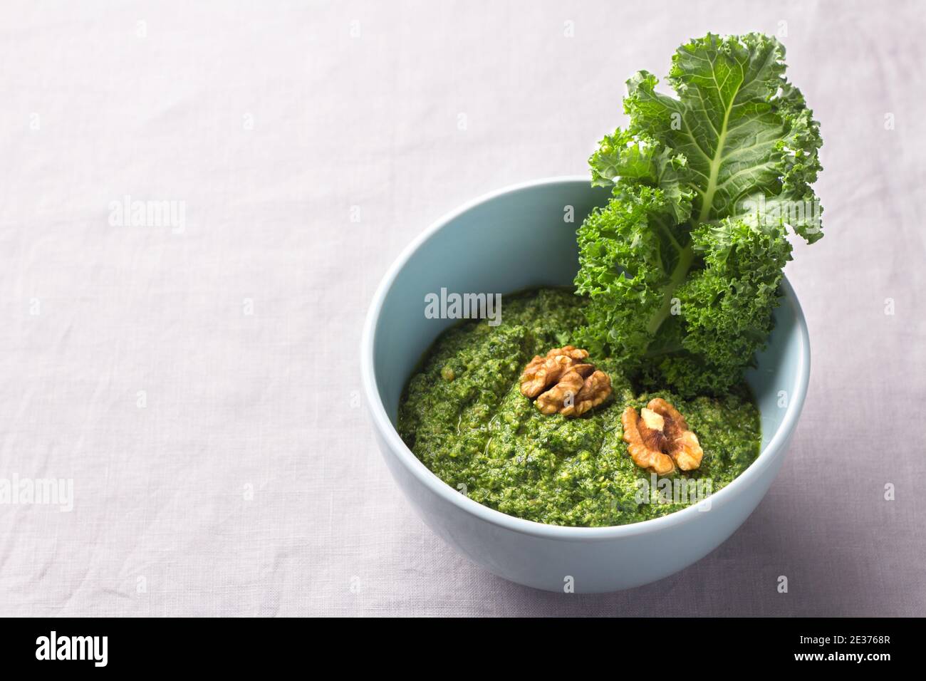 Grünes Pesto von Grünkohl, Walnüssen, Knoblauch und Olivenöl auf grauem Hintergrund. Leckeres gesundes Essen. Freiraum Stockfoto